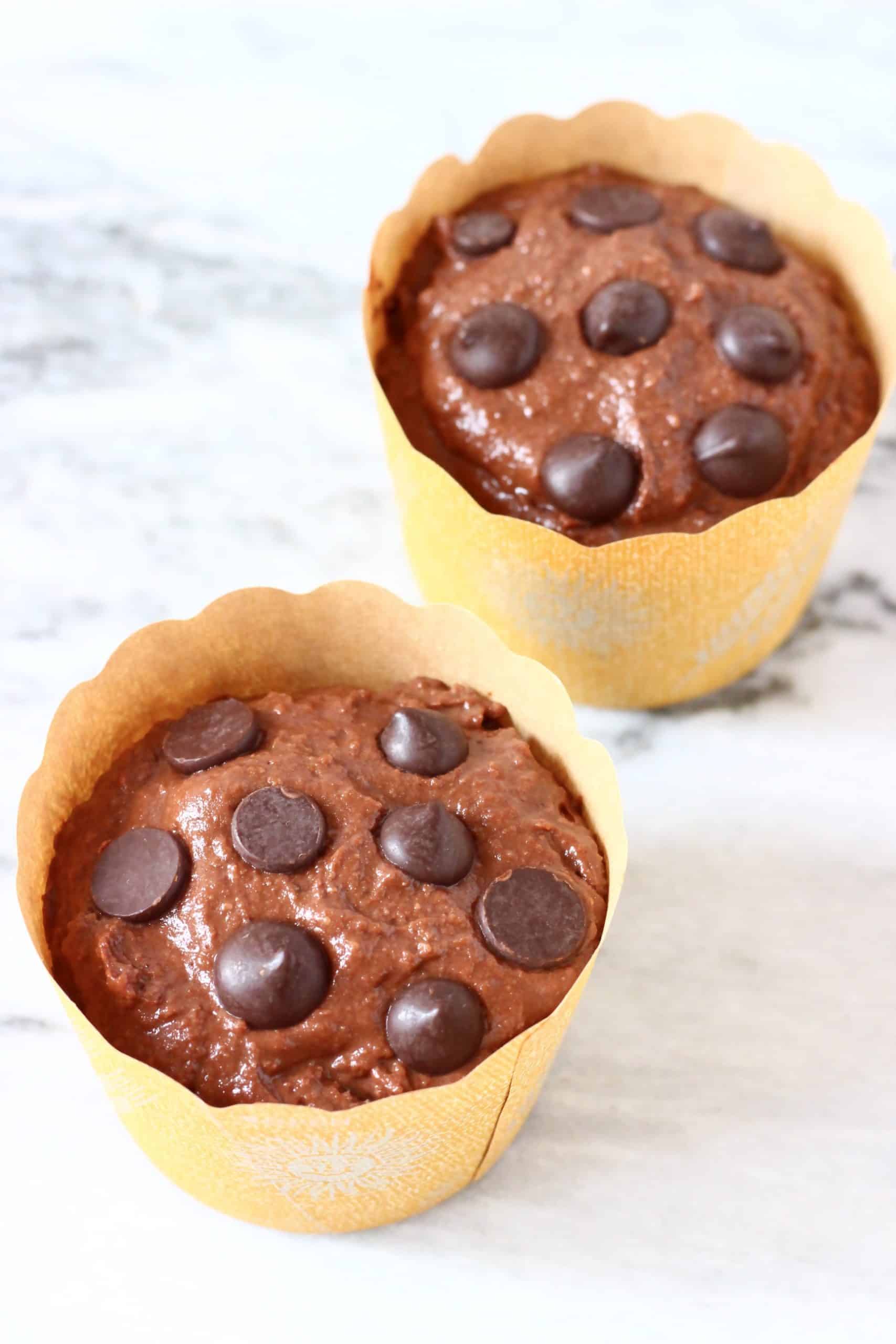 Raw gluten-free vegan chocolate pumpkin muffin batter in muffin cases topped with chocolate chips