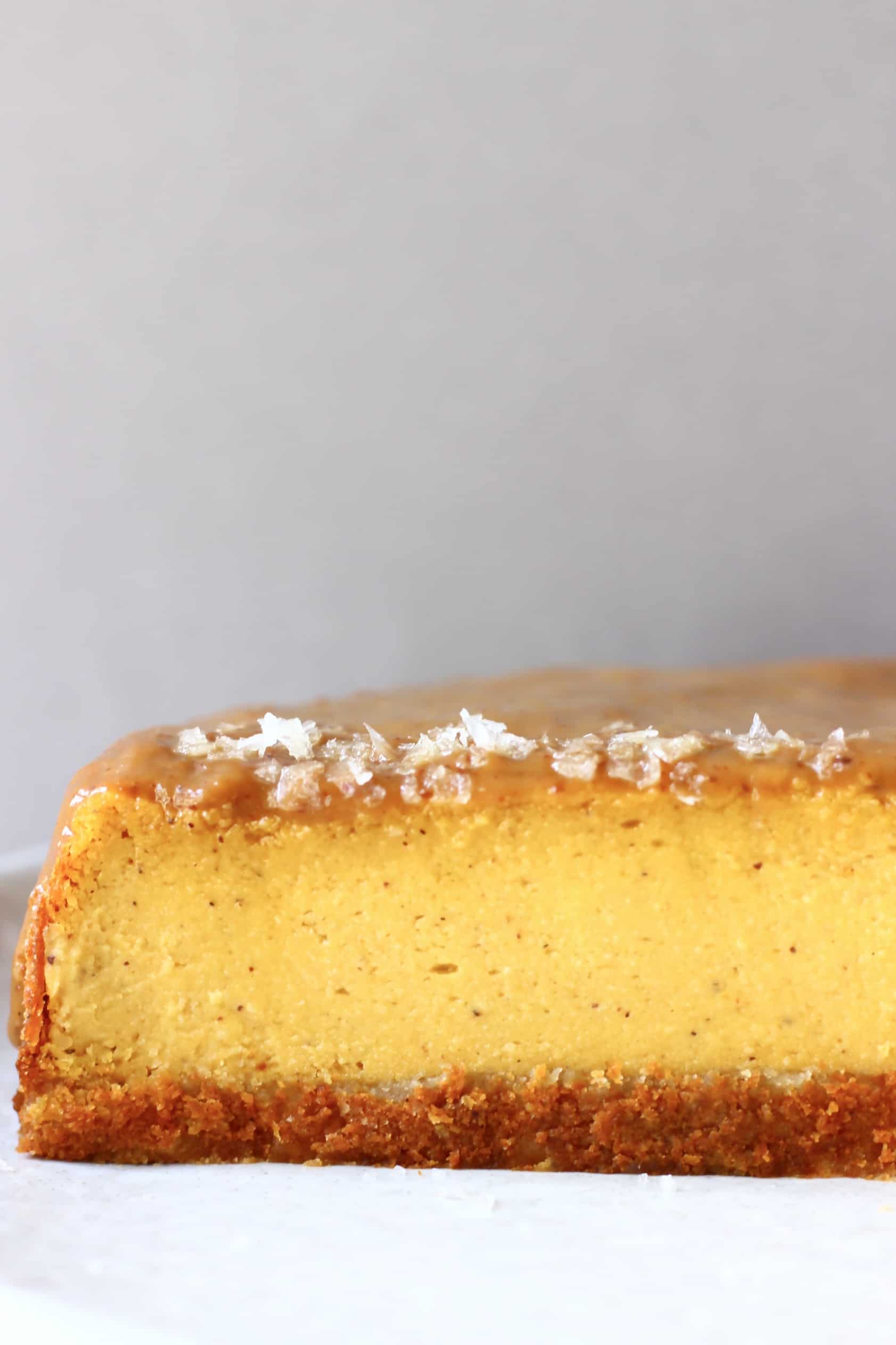 A sliced vegan baked pumpkin cheesecake topped with salted caramel sauce
