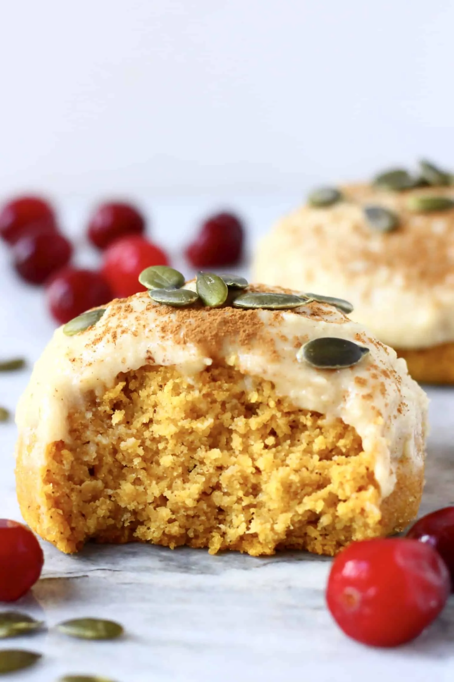 A halved gluten-free vegan pumpkin cookie topped with white frosting and pumpkin seeds