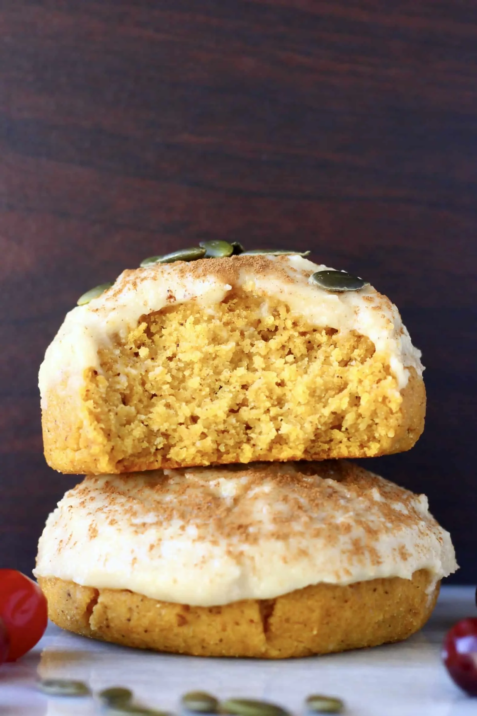 Two gluten-free vegan pumpkin cookies with frosting stacked on top of each other, one cut in half