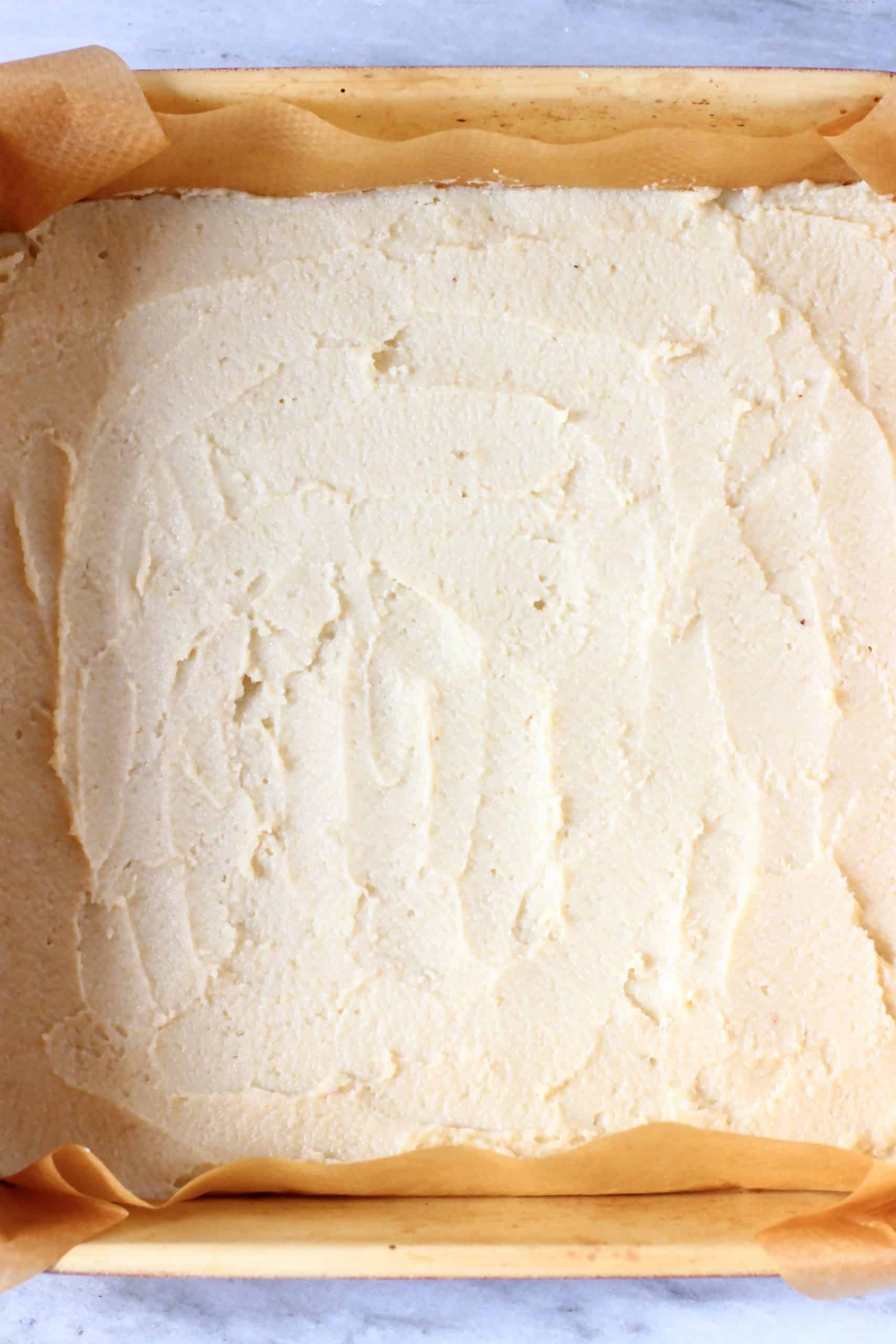 Raw coffee cake batter in a square baking tin lined with baking paper