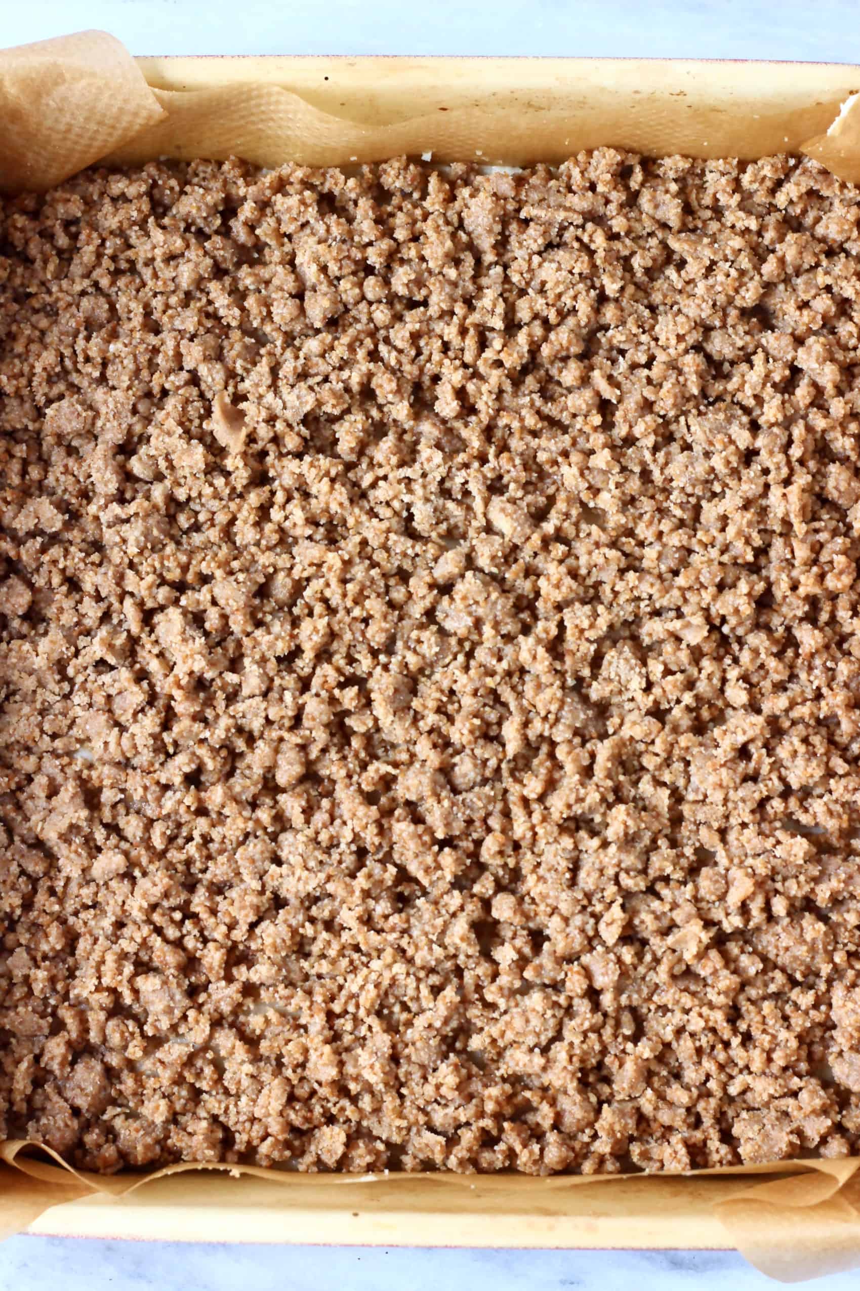 Raw vegan coffee cake batter with raw streusel topping in a square baking tin