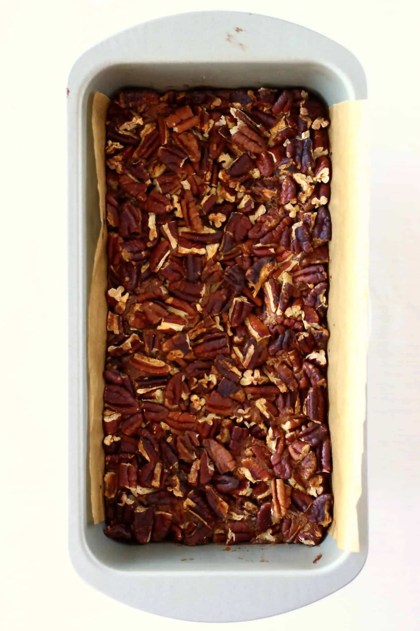 Baked vegan pecan pie bars in a loaf tin lined with baking paper