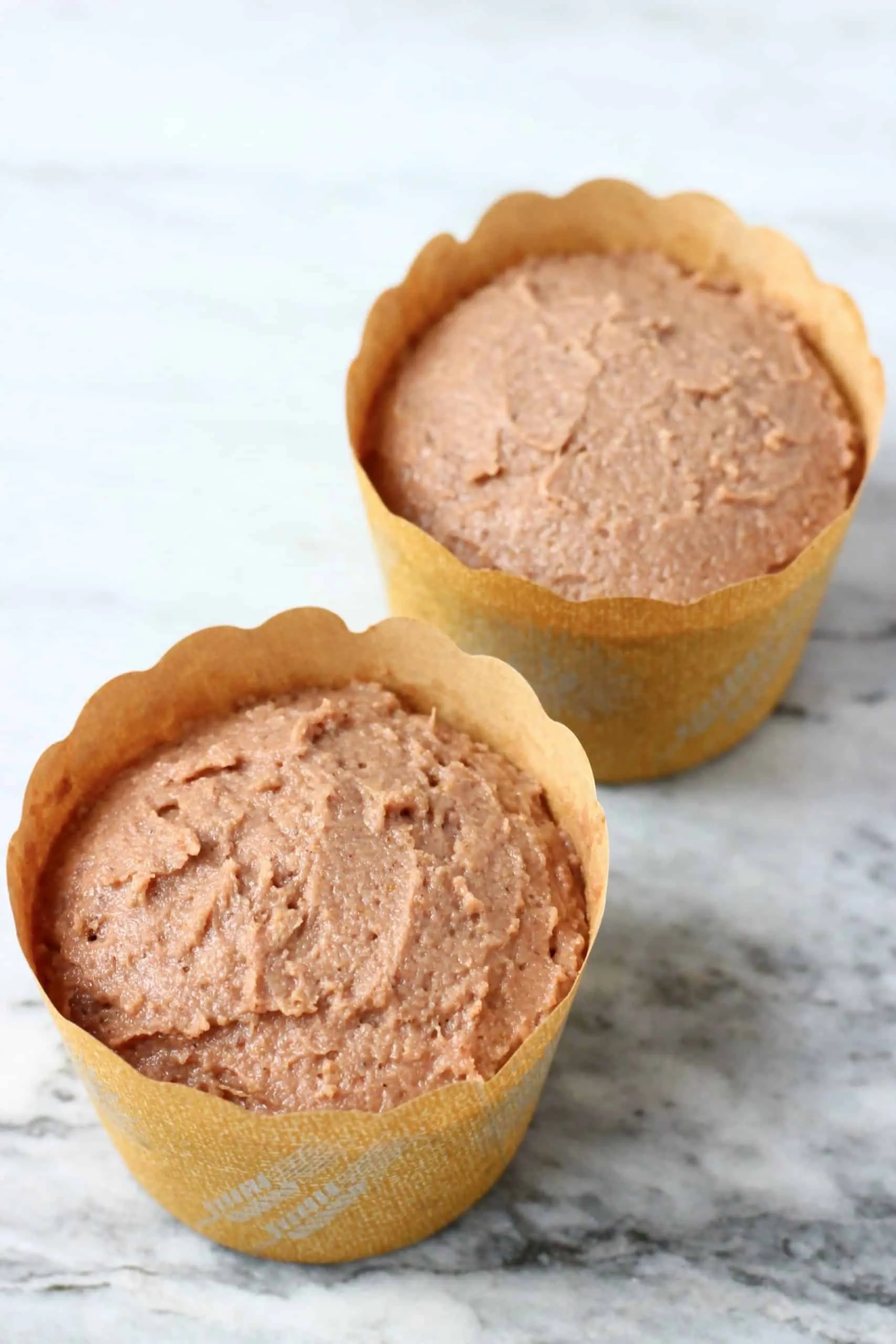 Raw gluten-free vegan gingerbread muffins batter in two brown muffin cases