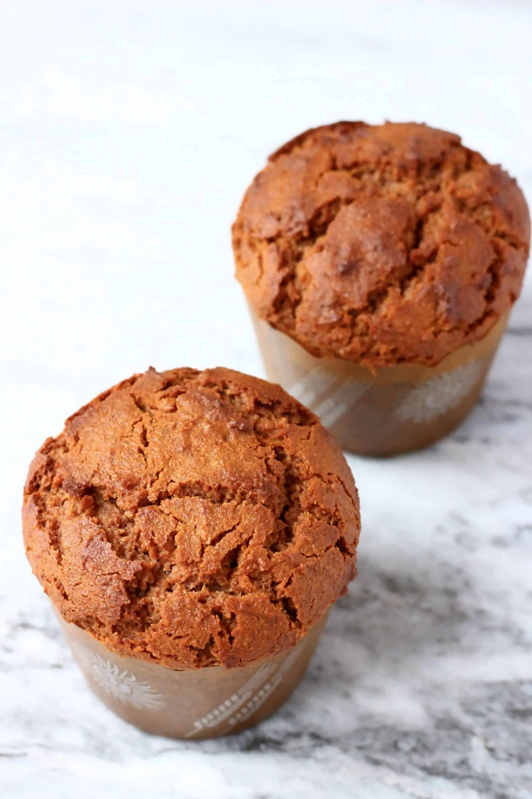 Two gluten-free vegan gingerbread muffins in brown muffin cases