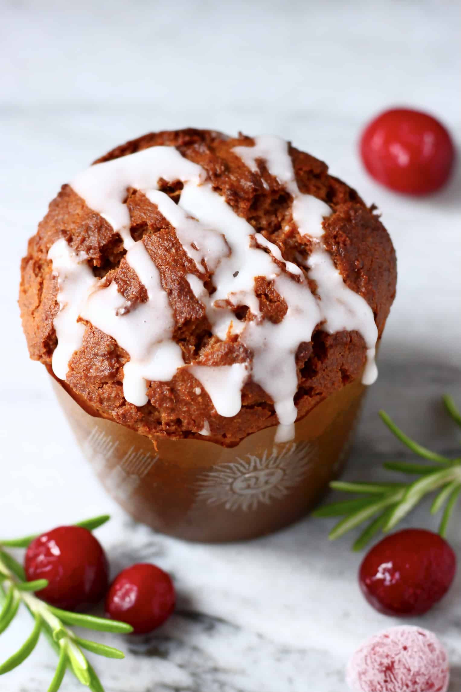 A gluten-free vegan gingerbread muffin in a brown muffin case drizzled with icing
