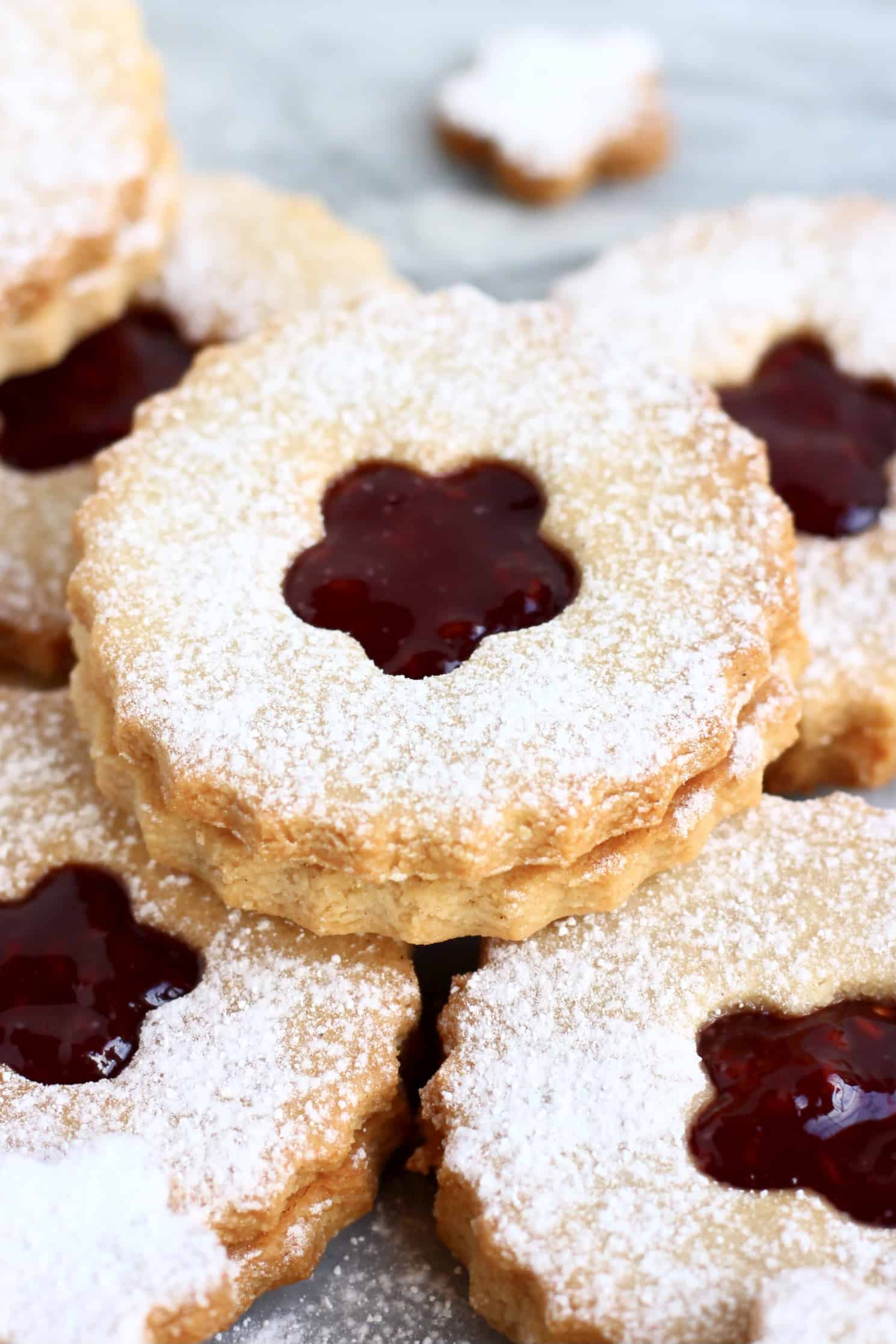 Seven gluten-free vegan linzer cookies filled with raspberry jam