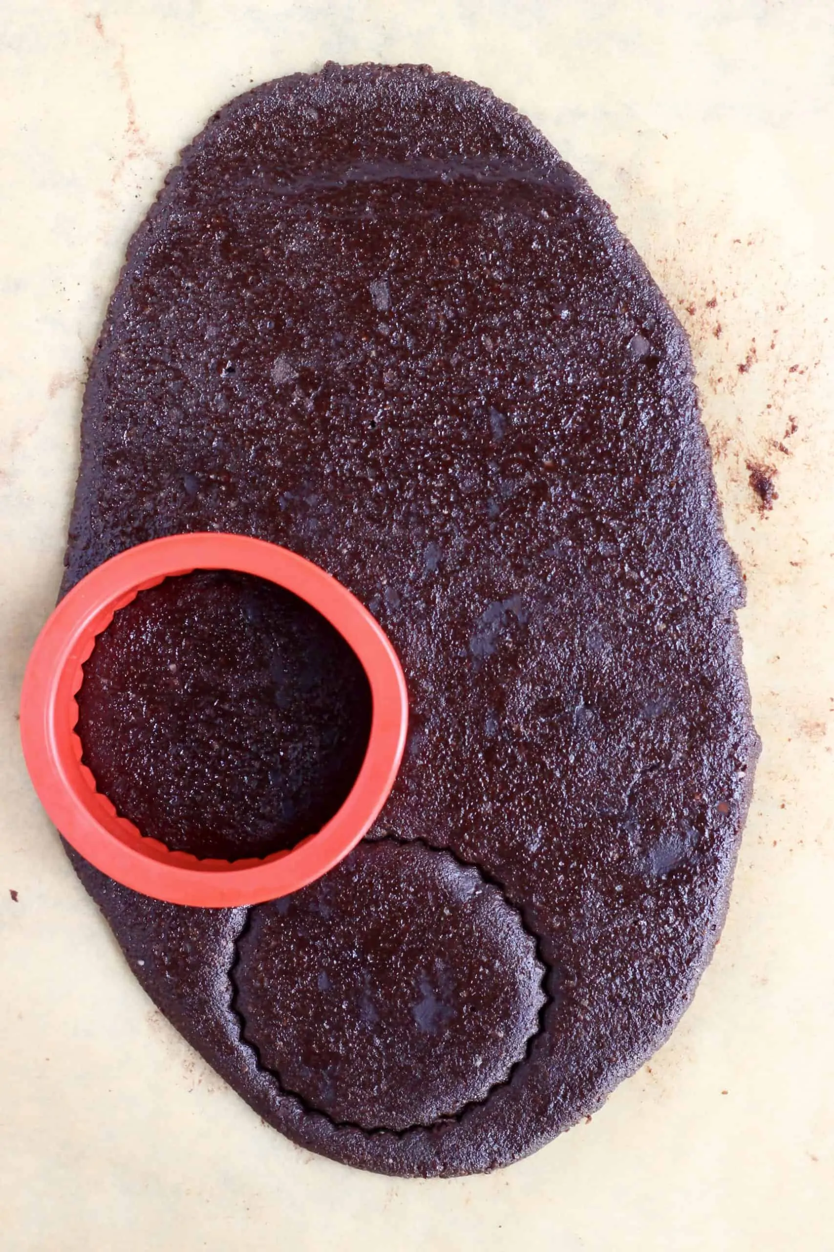 Raw gluten-free vegan homemade oreos cookie dough rolled out with a circular cookie cutter cutting out shapes