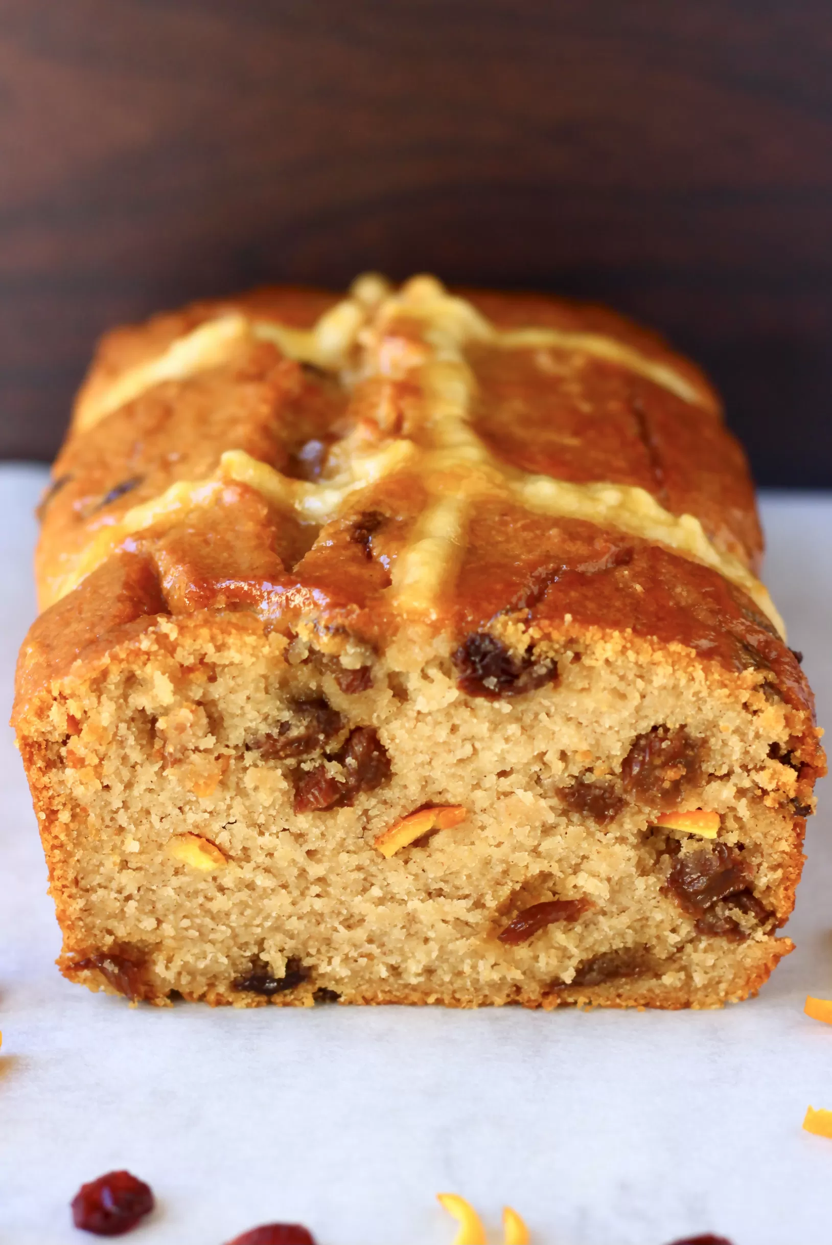 A sliced gluten-free vegan hot cross bun loaf with raisins and orange peel