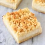 Three vegan lemon cheesecake crumble bars on a marble background