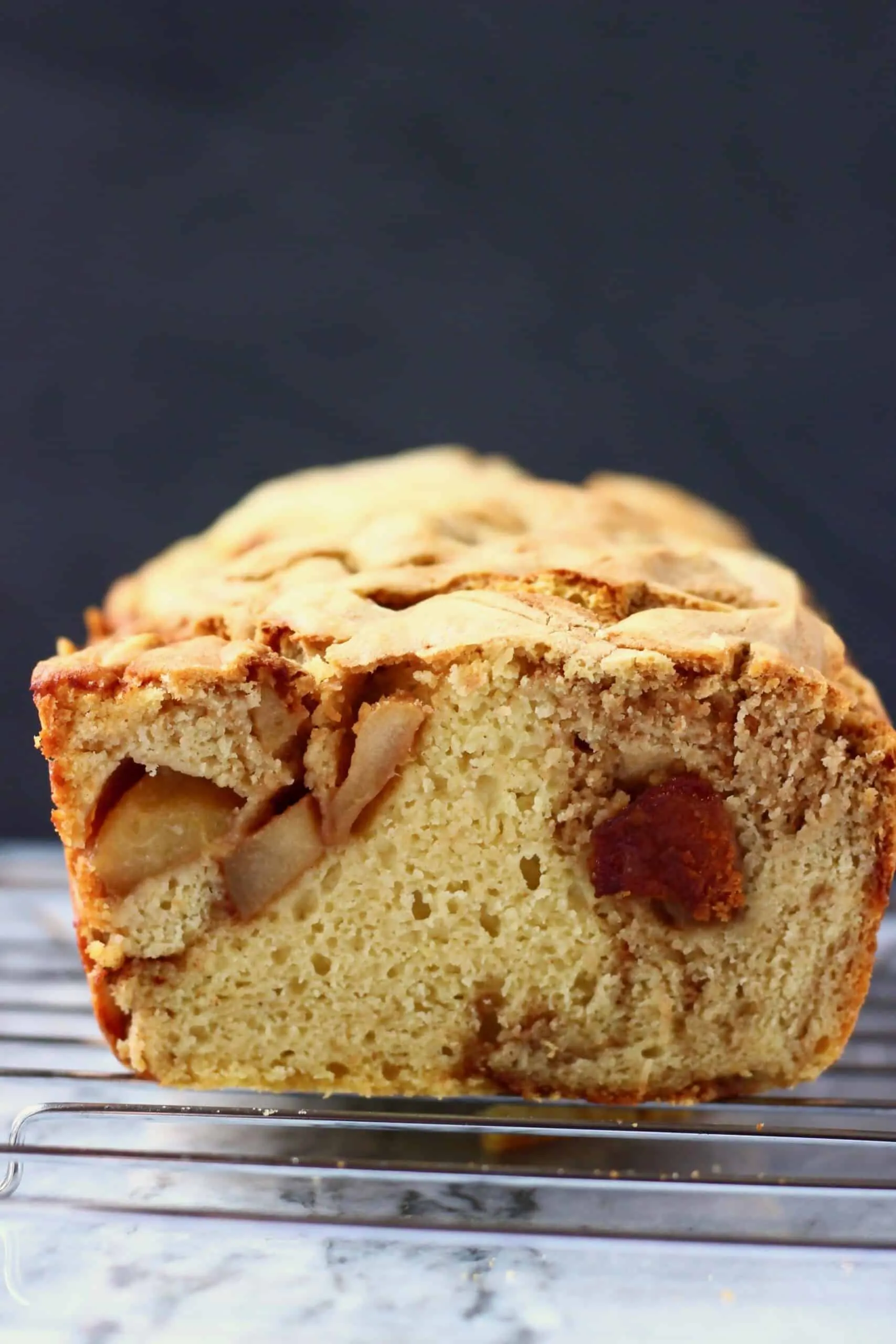Sliced gluten-free vegan apple bread loaf against a black background