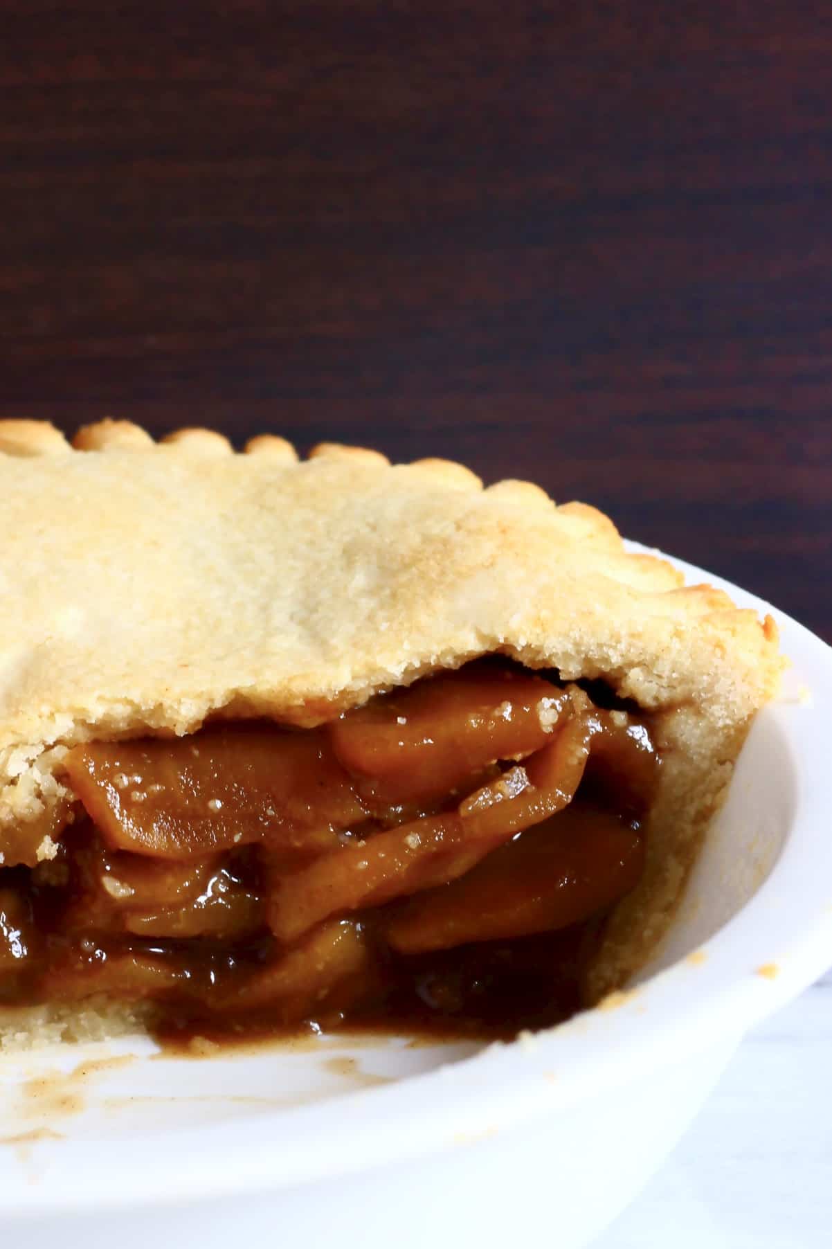 A sliced gluten-free vegan apple pie in a white pie dish