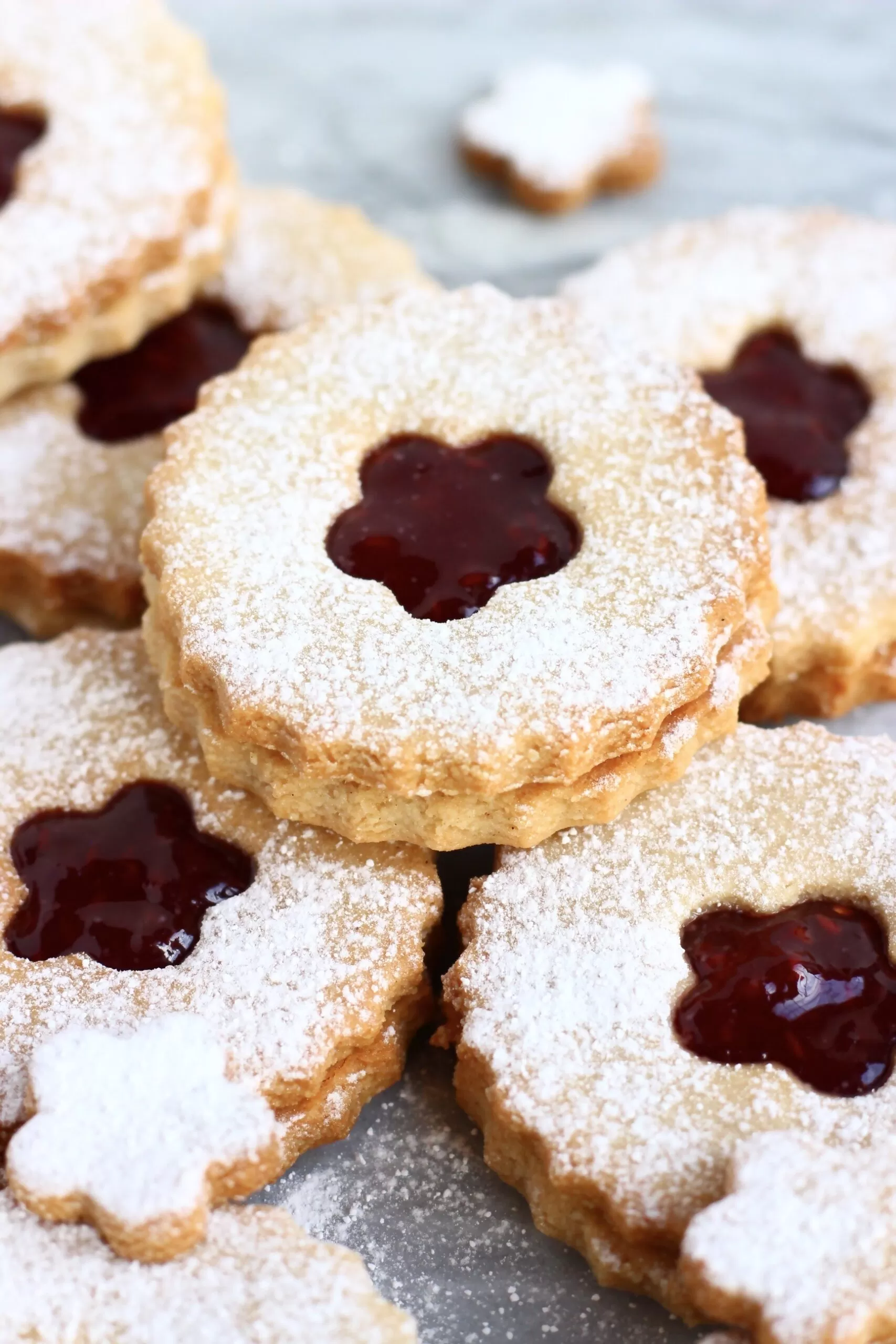 Six gluten-free vegan linzer cookies filled with raspberry jam