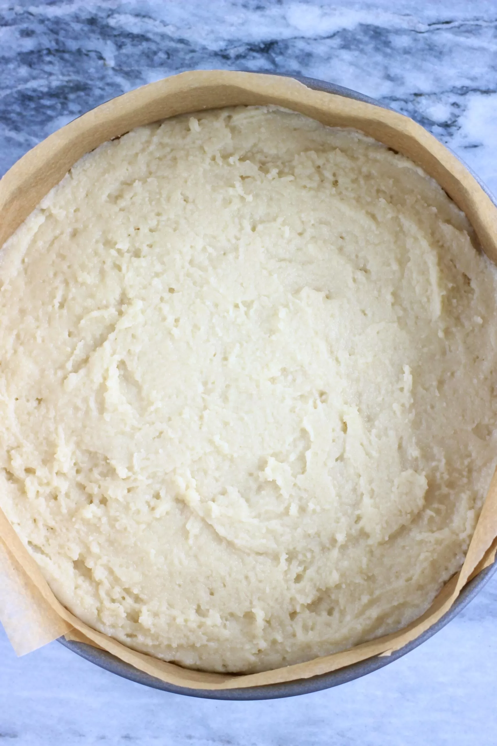 Raw gluten-free vegan almond cake batter in a springform baking tin lined with baking paper