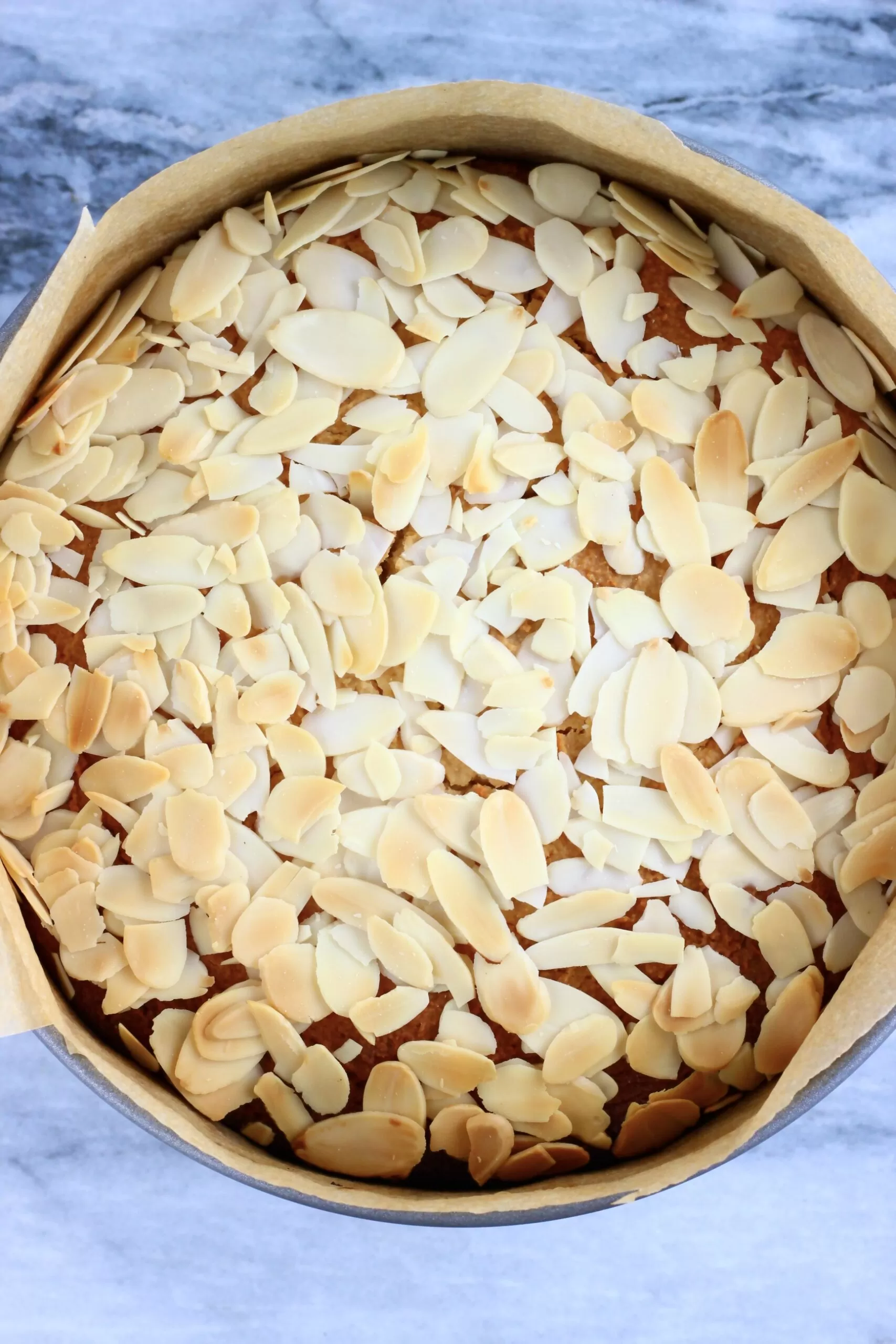 Baked gluten-free vegan almond cake in a springform baking tin lined with baking paper