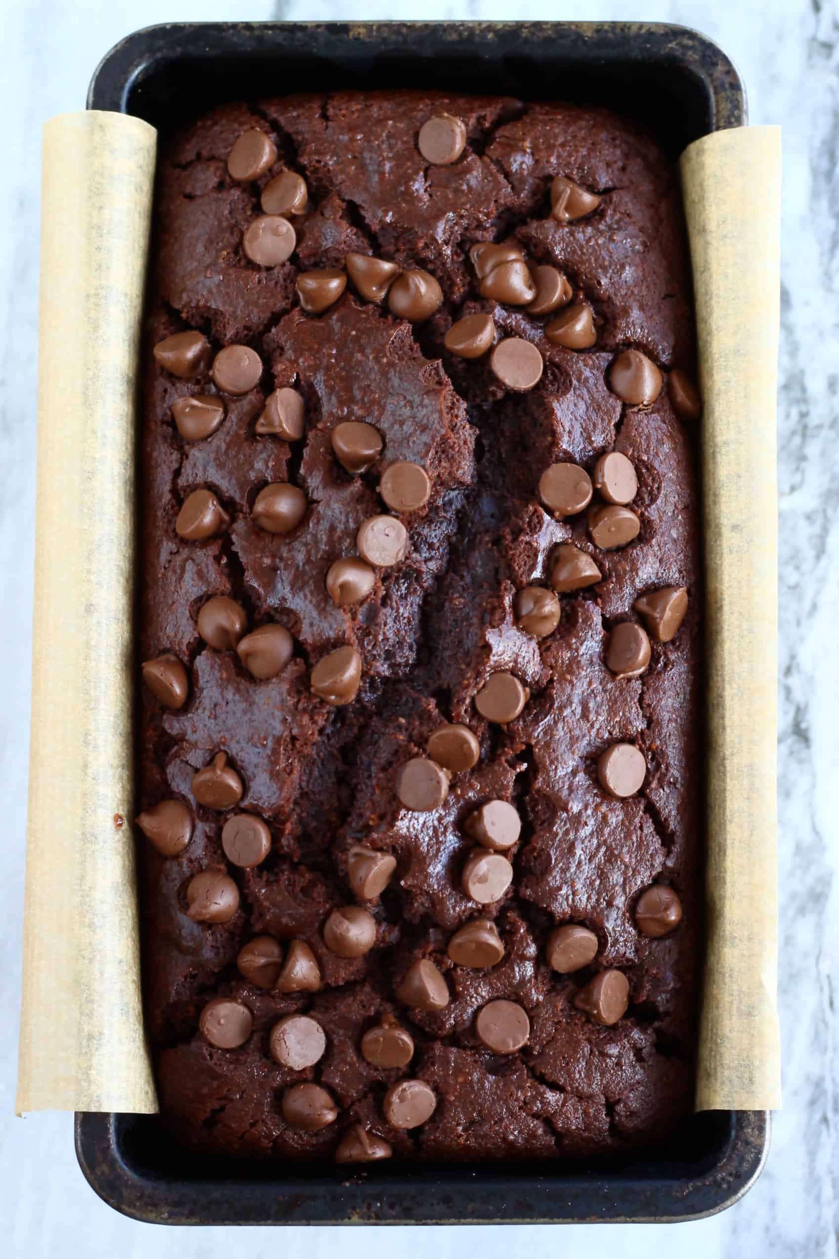 A loaf of gluten-free vegan chocolate bread in a loaf tin lined with baking paper