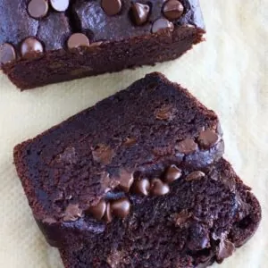 A loaf of gluten-free vegan chocolate bread with two slices next to it