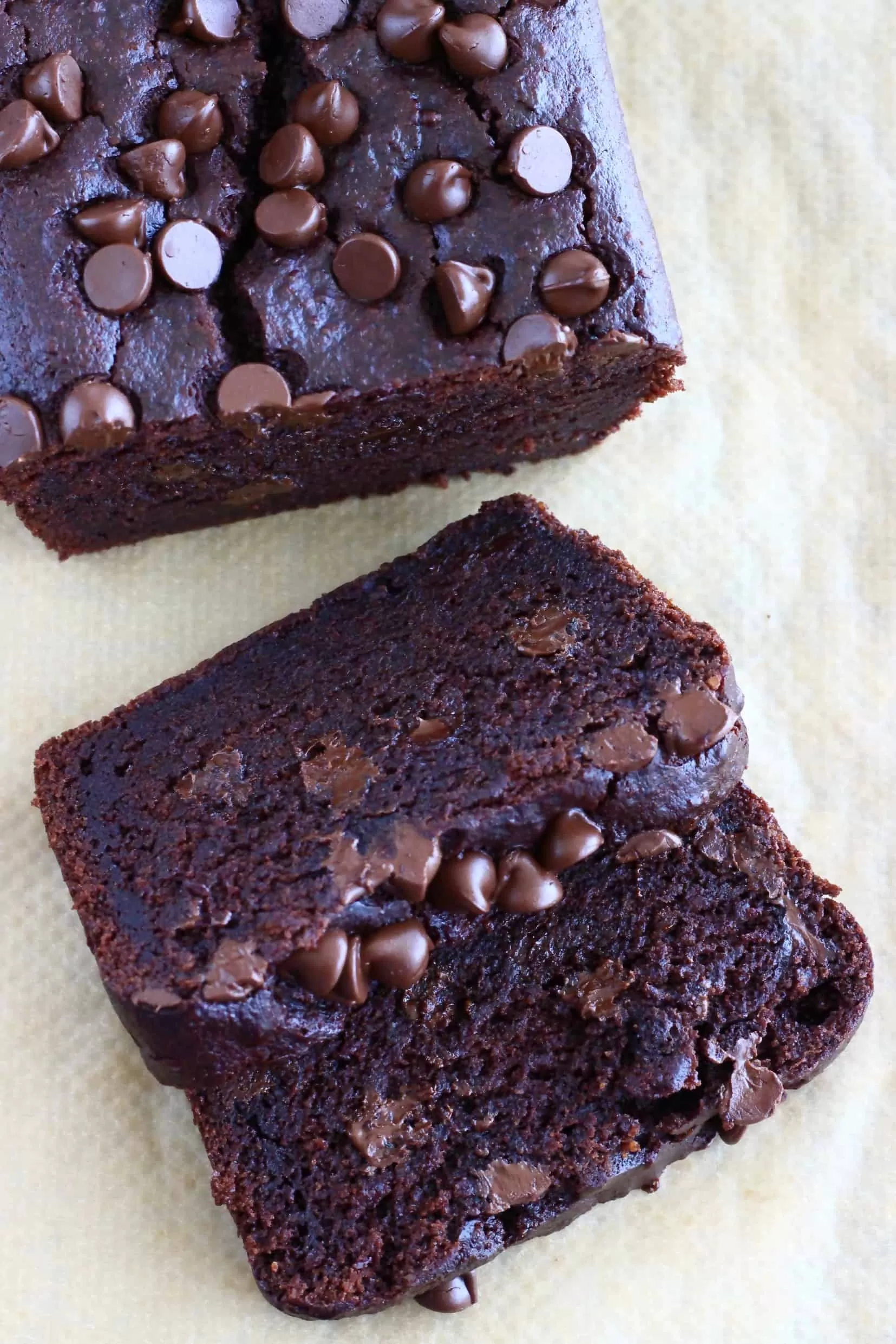 A loaf of gluten-free vegan chocolate bread with two slices next to it