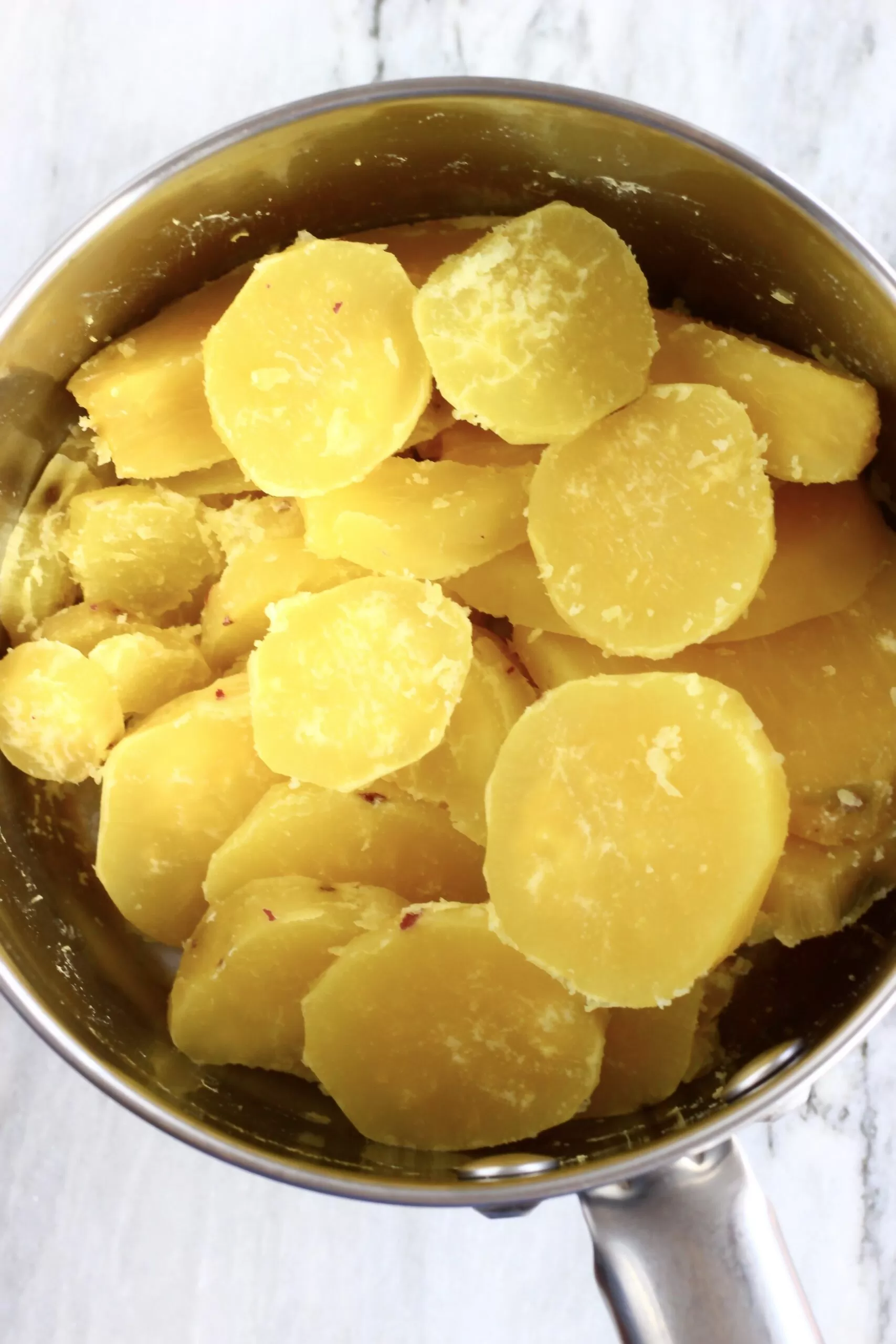 Sliced cooked white sweet potatoes in a silver pot