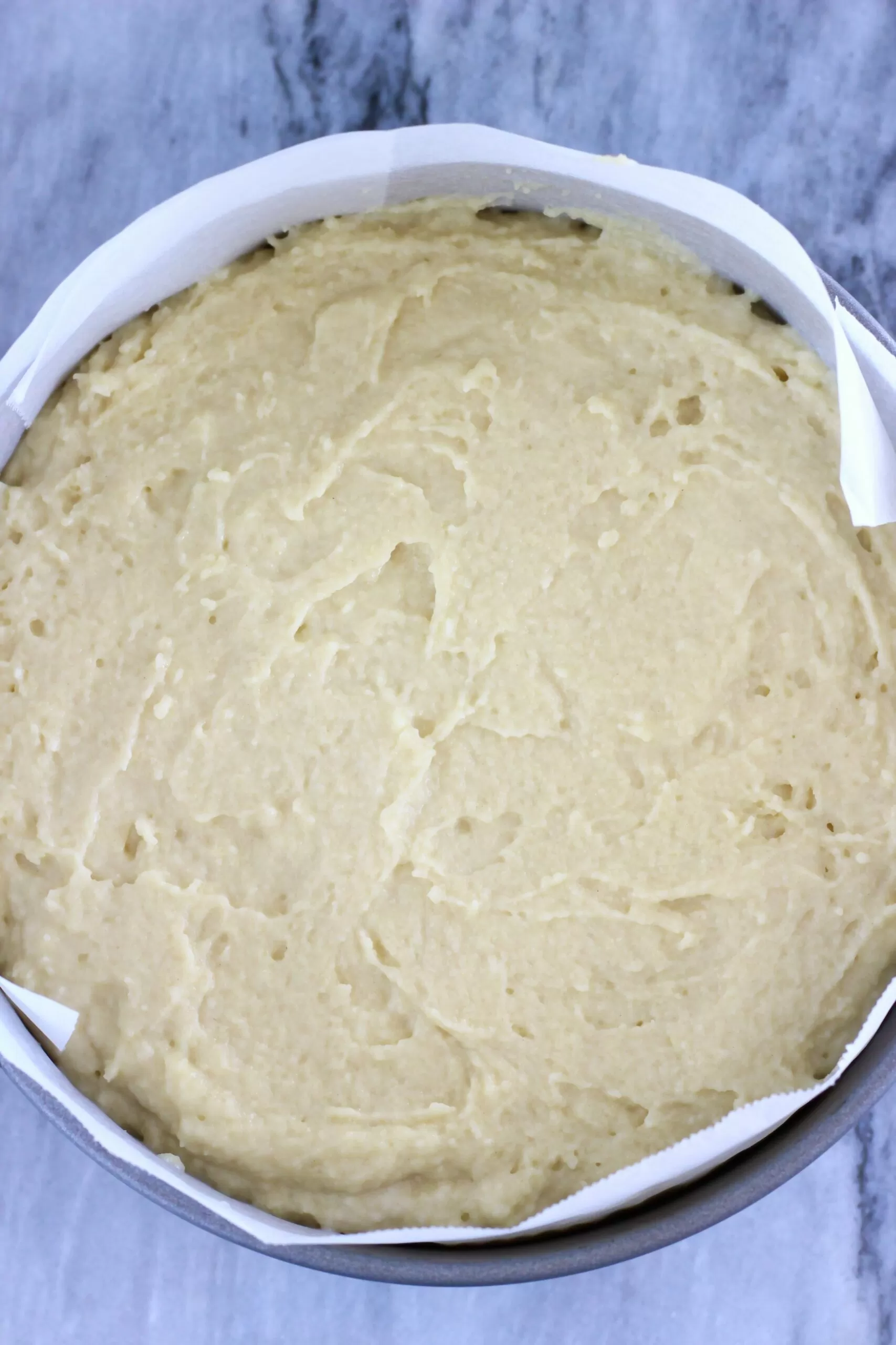 Raw gluten-free vegan yogurt cake batter in a round baking tin lined with baking paper
