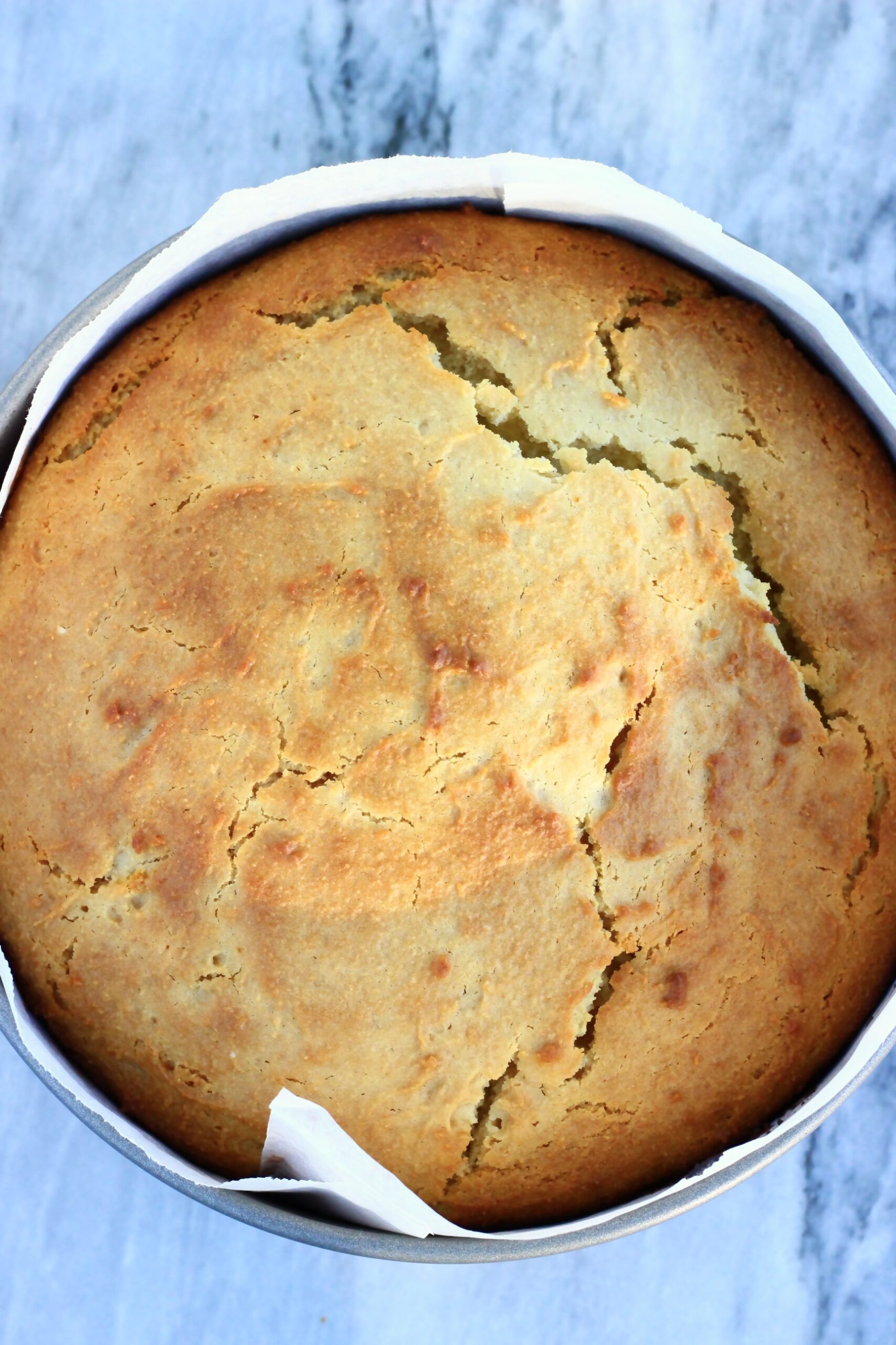 A baked gluten-free vegan yogurt cake in a round baking tin lined with baking paper