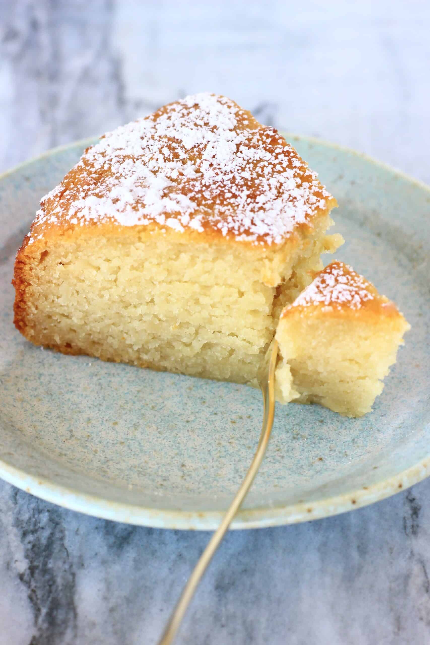 A slice of gluten-free vegan yogurt cake on a plate with a fork taking a bite out of it