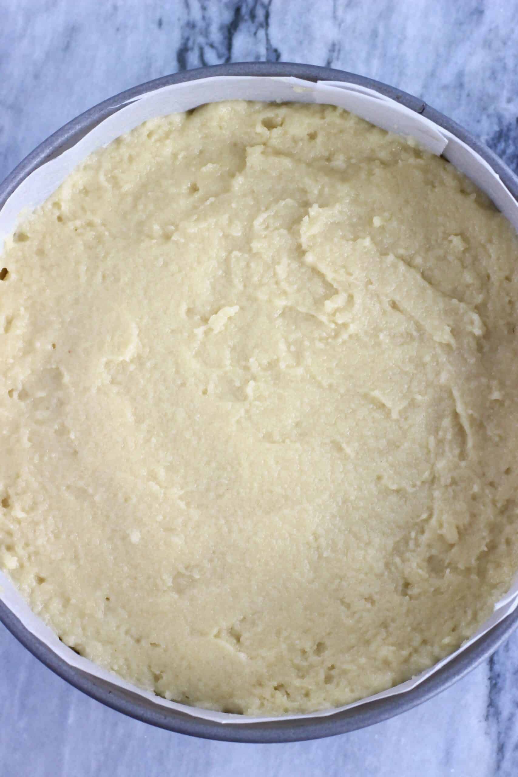 Raw gluten-free vegan olive oil cake batter in a round springform baking tin lined with baking paper