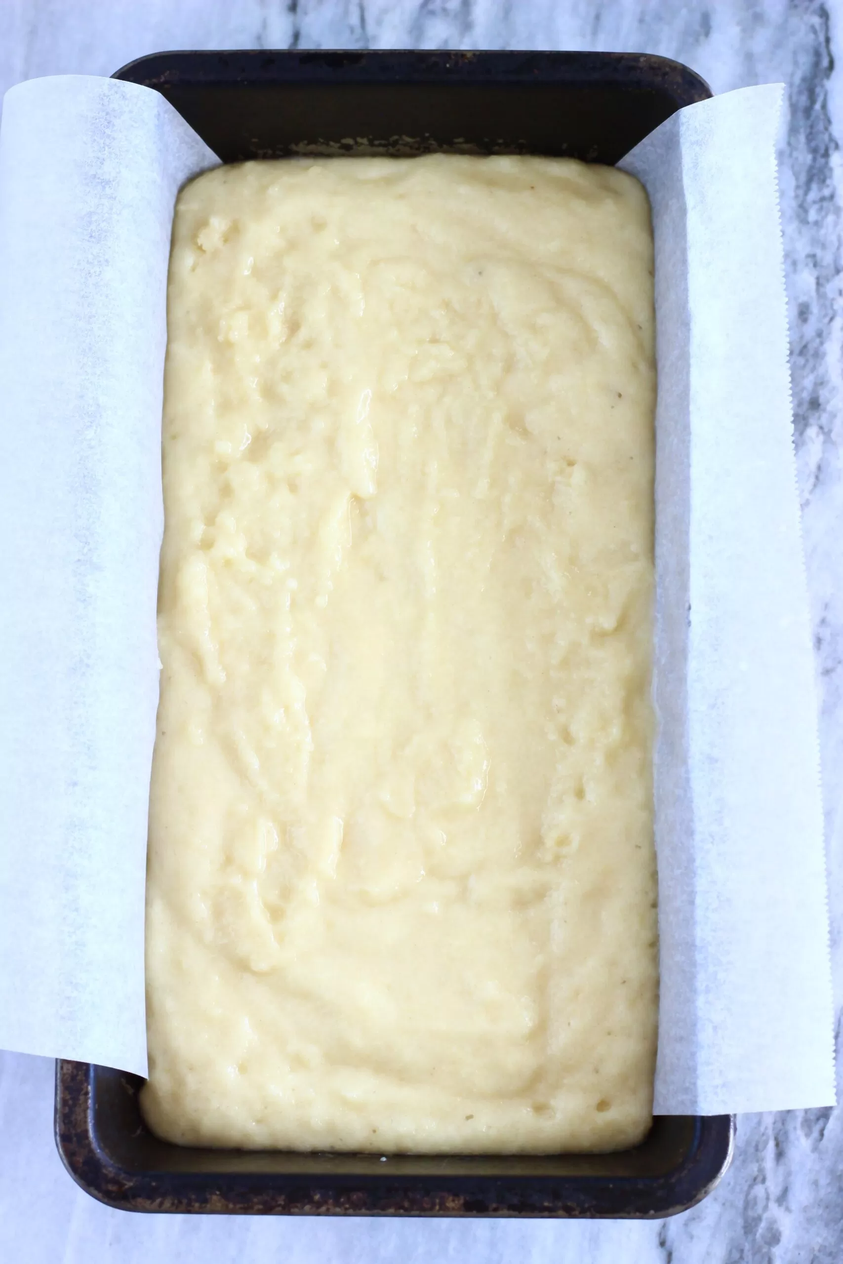 Raw vegan lemon drizzle loaf cake batter in a loaf tin lined with baking paper