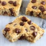 Three gluten-free vegan oatmeal chocolate chip cookie bars with a bite taken out of one