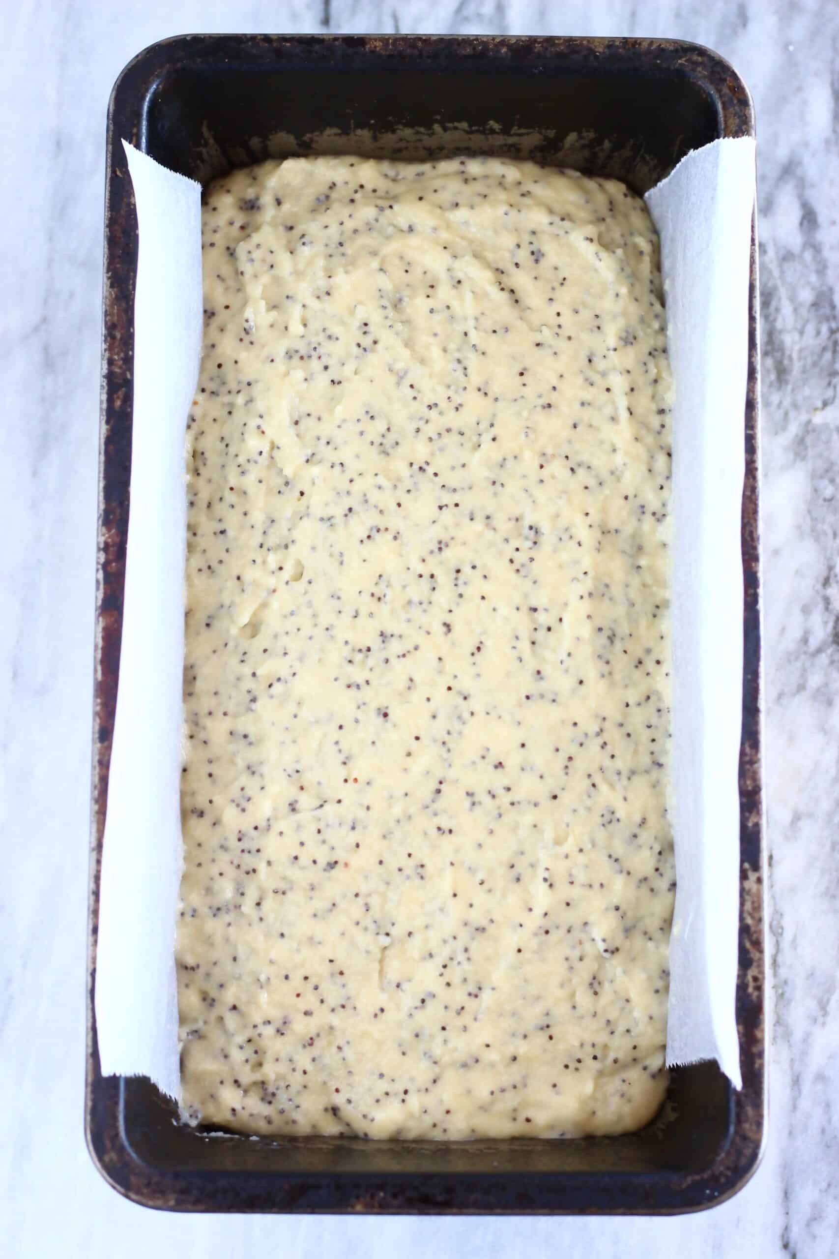 Raw gluten-free vegan orange poppy seed bread batter in a loaf tin lined with baking paper