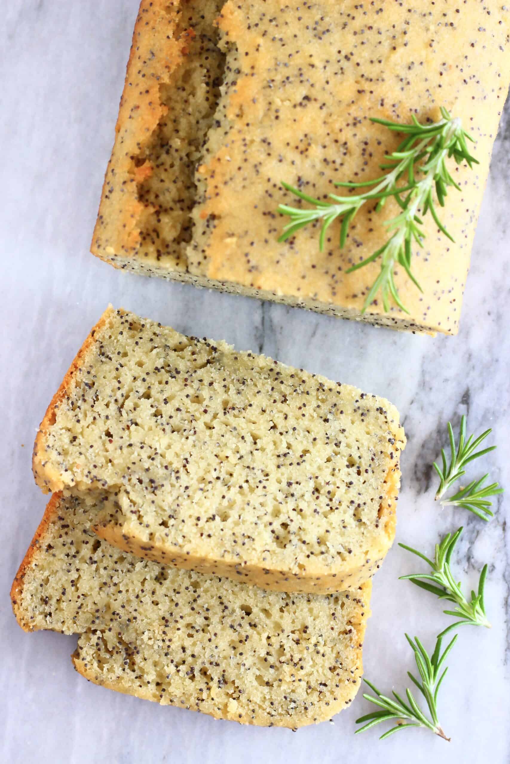 A loaf of gluten-free vegan orange poppy seed bread with two slices next to it
