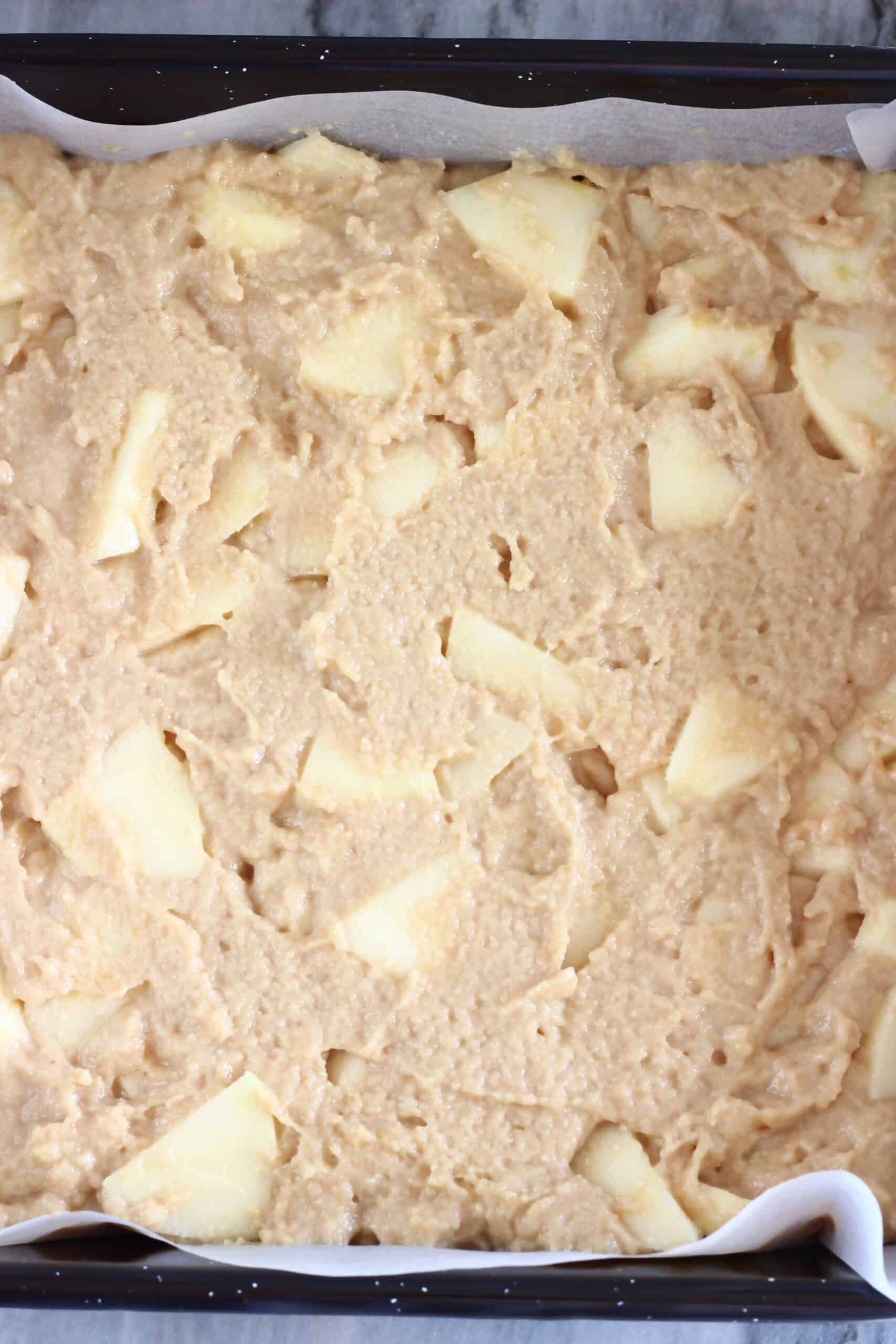 Raw gluten-free vegan apple snack cake batter in a square baking tin lined with baking paper