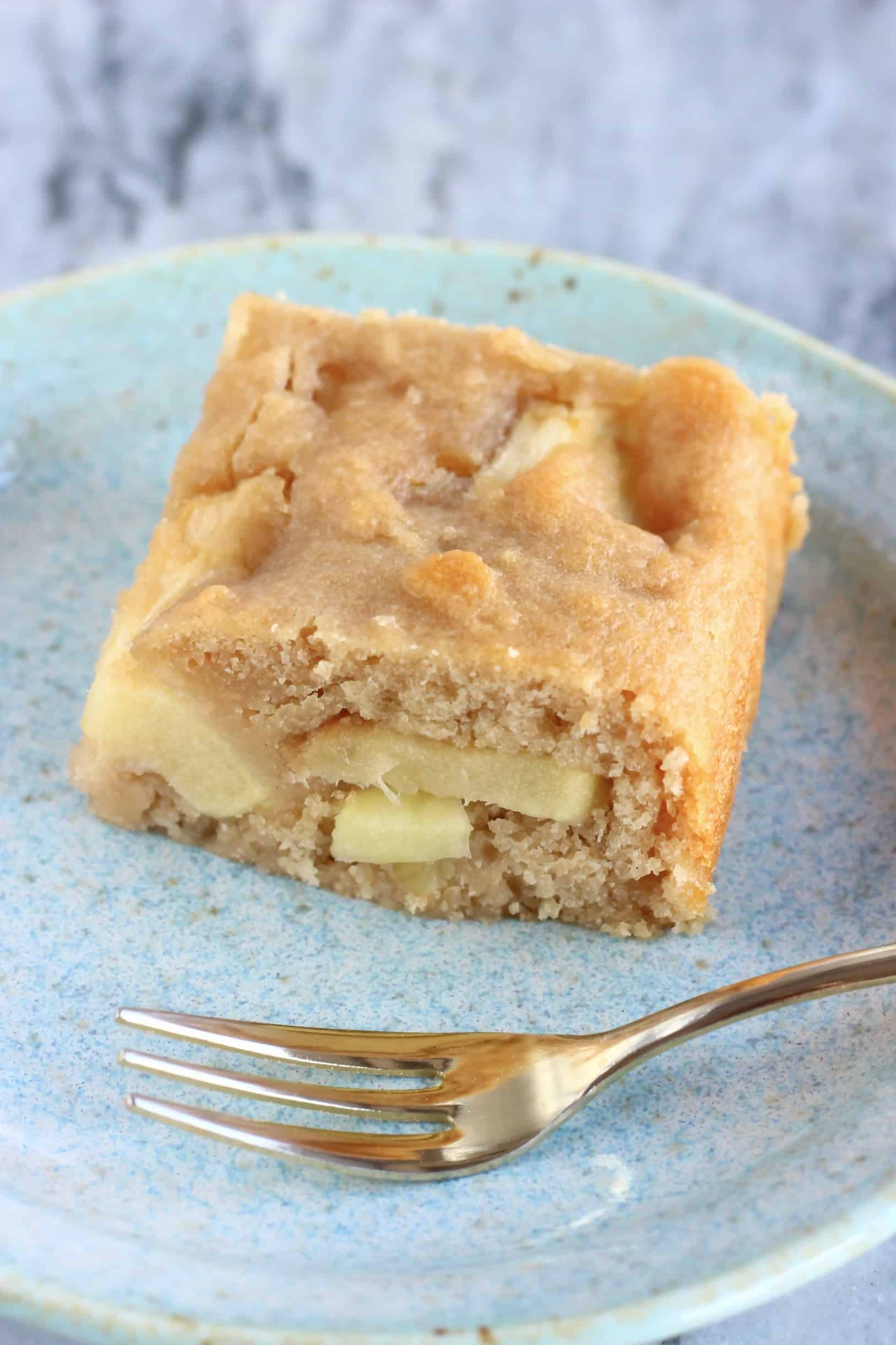 A square piece of gluten-free vegan apple snack cake on a plate with a fork