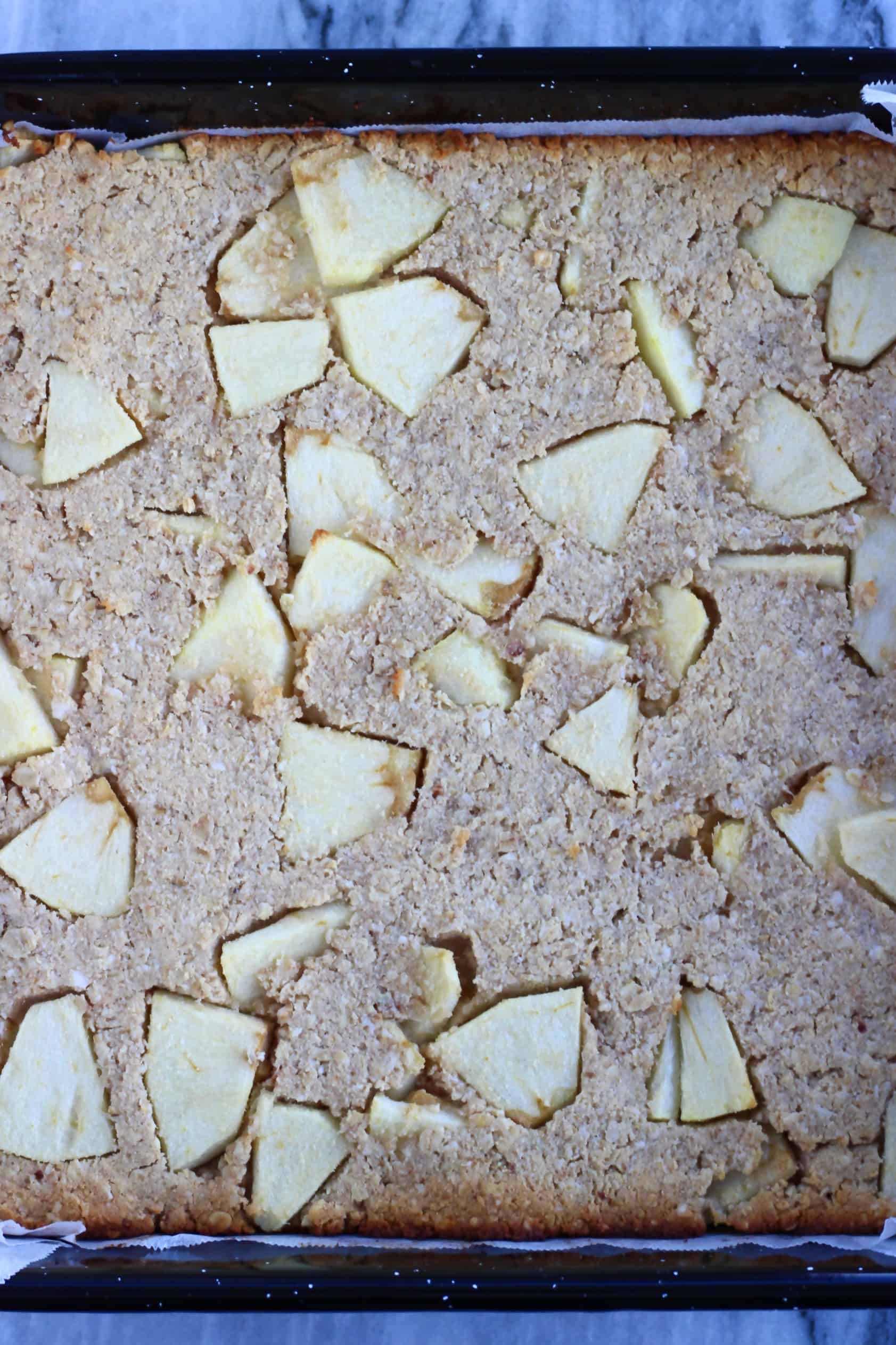 Baked vegan apple oatmeal bars in a square baking tin lined with baking paper