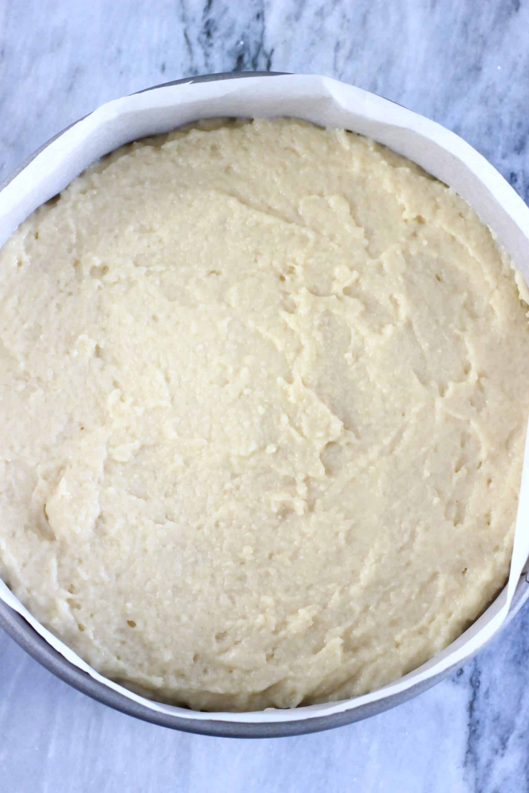 Raw gluten-free vegan lemon yogurt cake batter in a round springform baking tin lined with baking paper