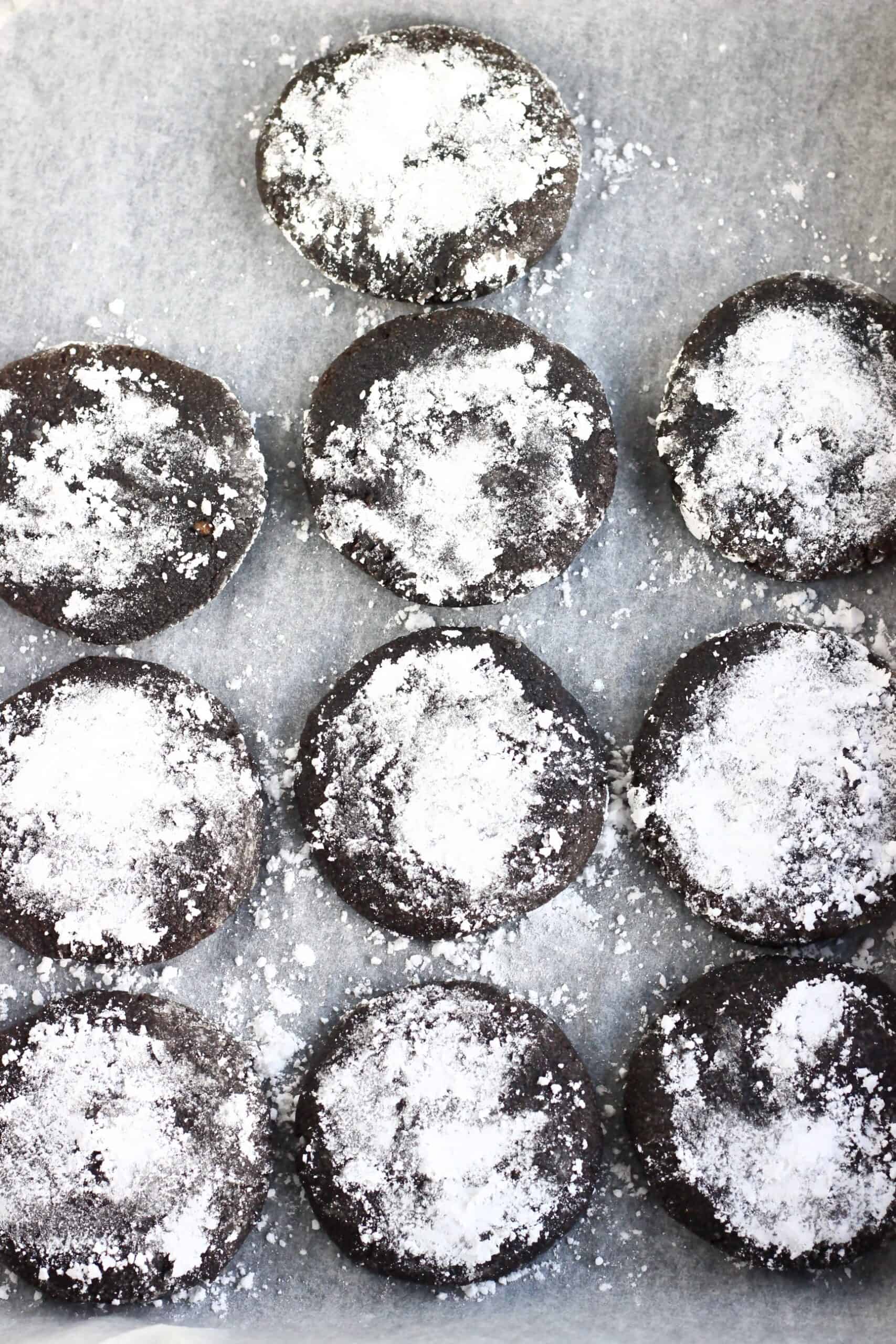 10 baked gluten-free vegan chocolate crinkle cookies on a baking tray lined with baking paper