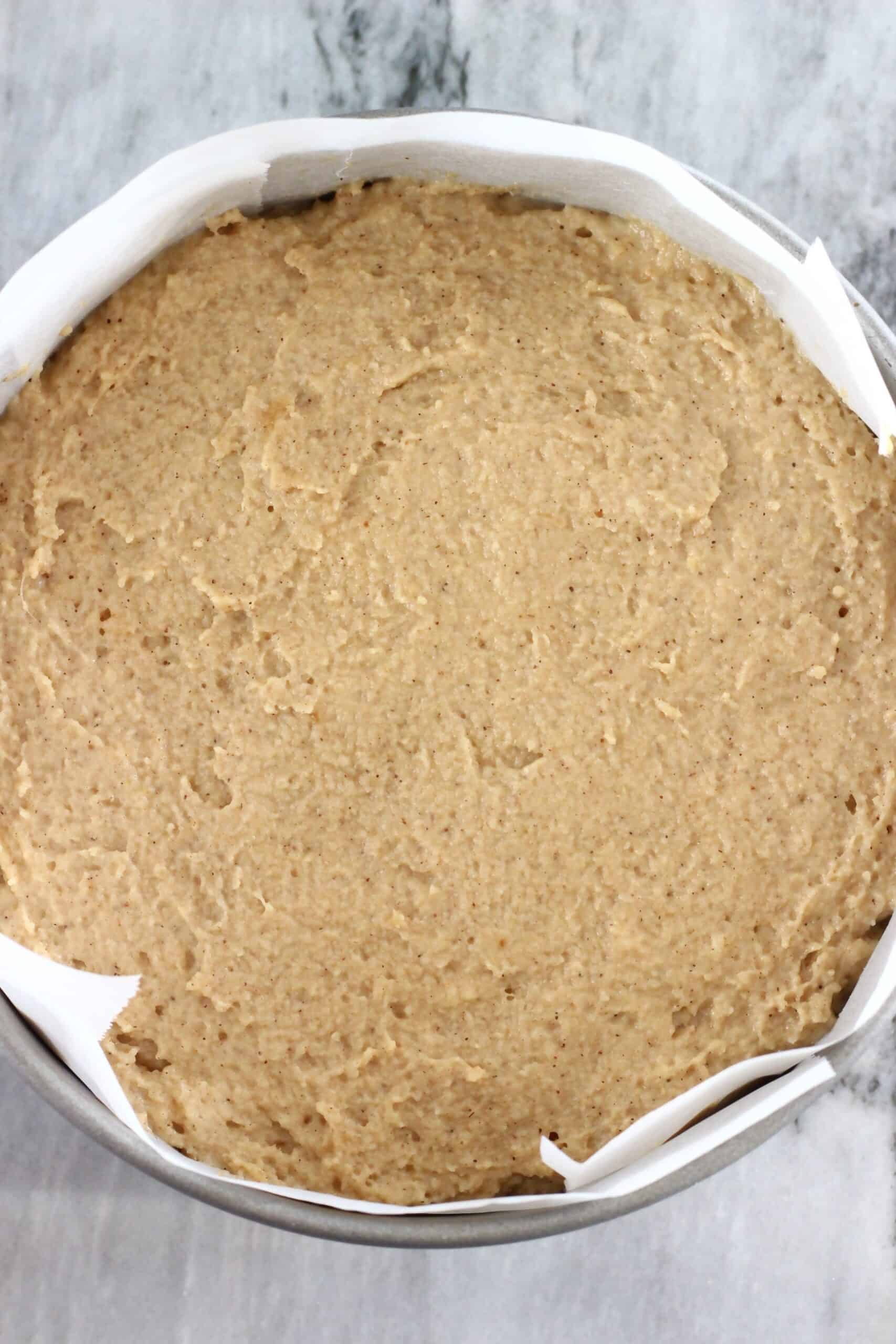 Raw gluten-free vegan ginger cake batter in a round springform baking tin lined with baking paper