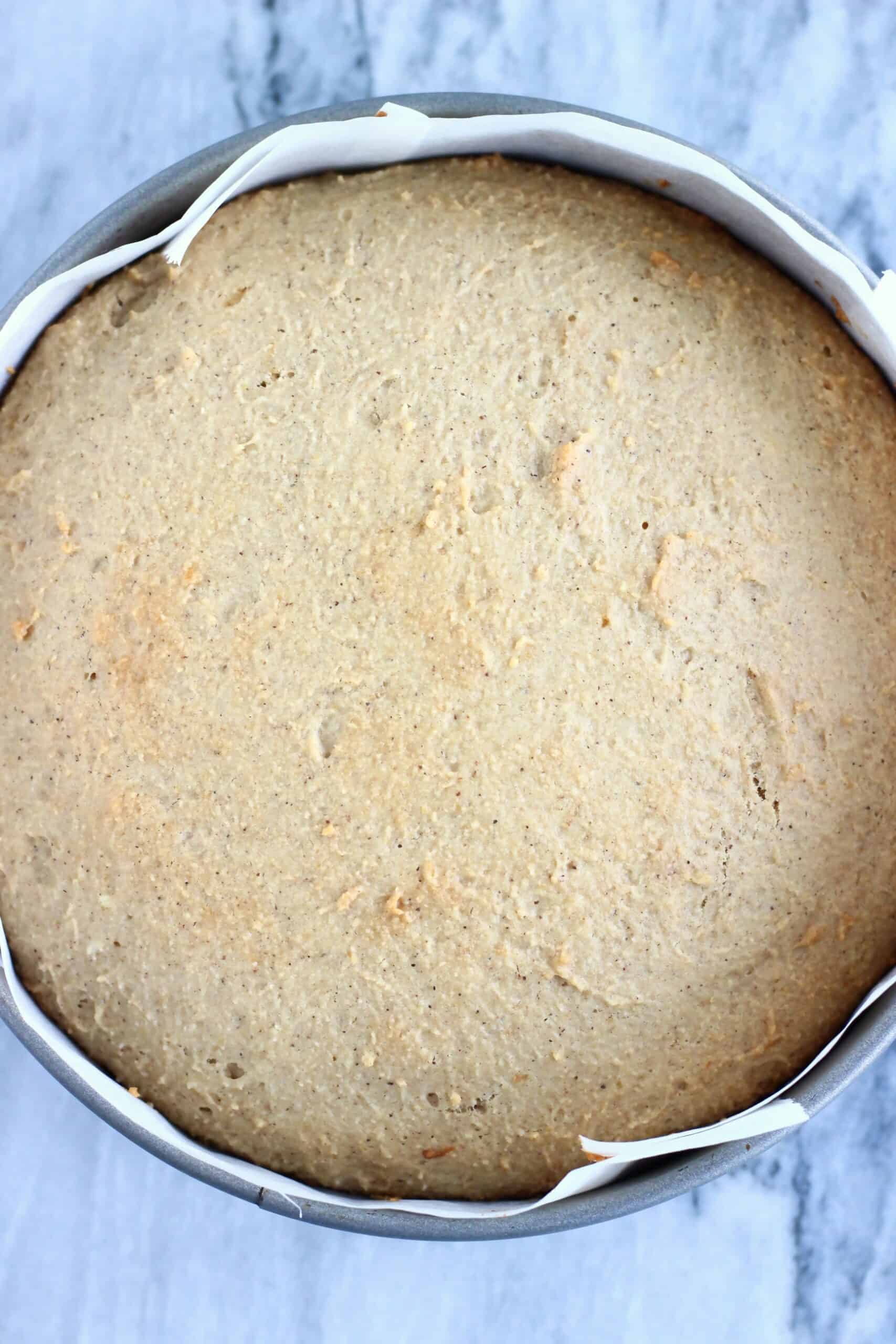 Baked gluten-free vegan ginger cake in a round springform baking tin lined with baking paper