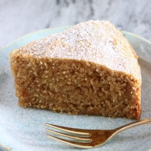 A slice of gluten-free vegan ginger cake on a plate with a gold fork