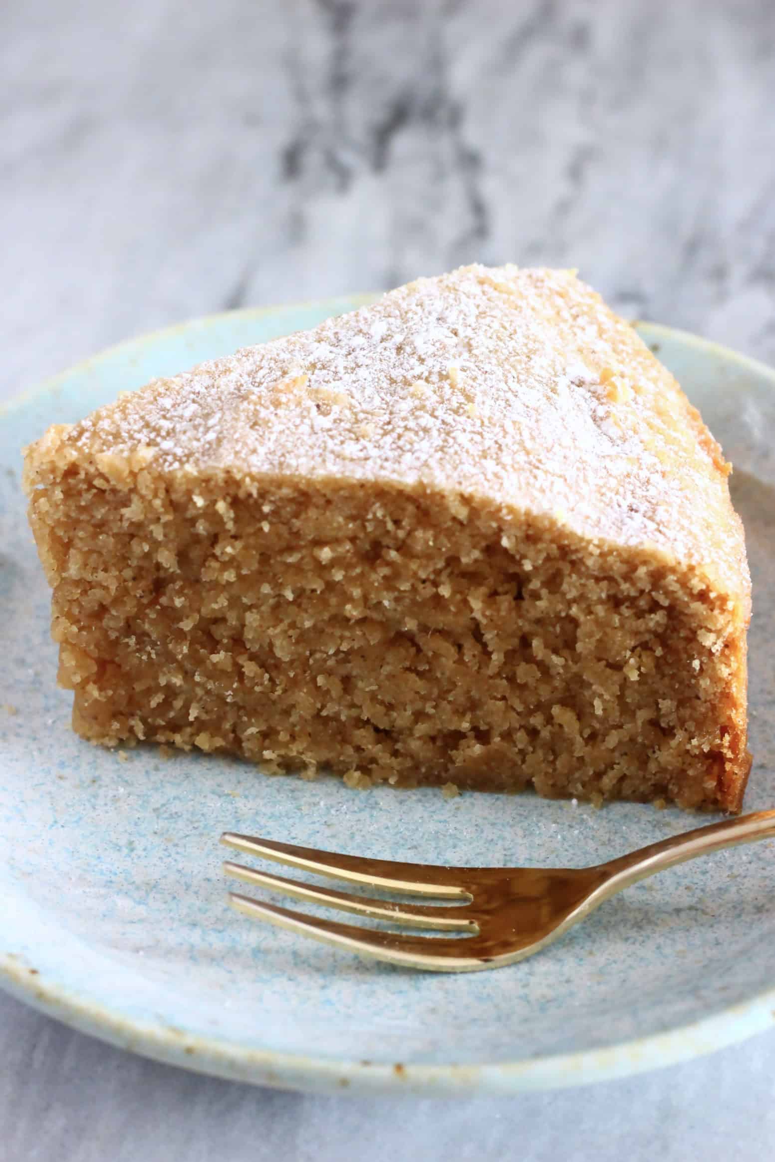 A slice of gluten-free vegan ginger cake on a plate with a gold fork