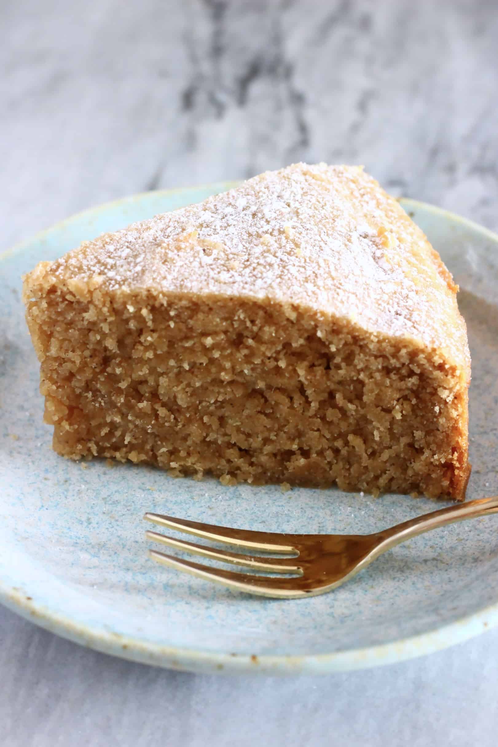 A slice of gluten-free vegan ginger cake on a plate with a gold fork