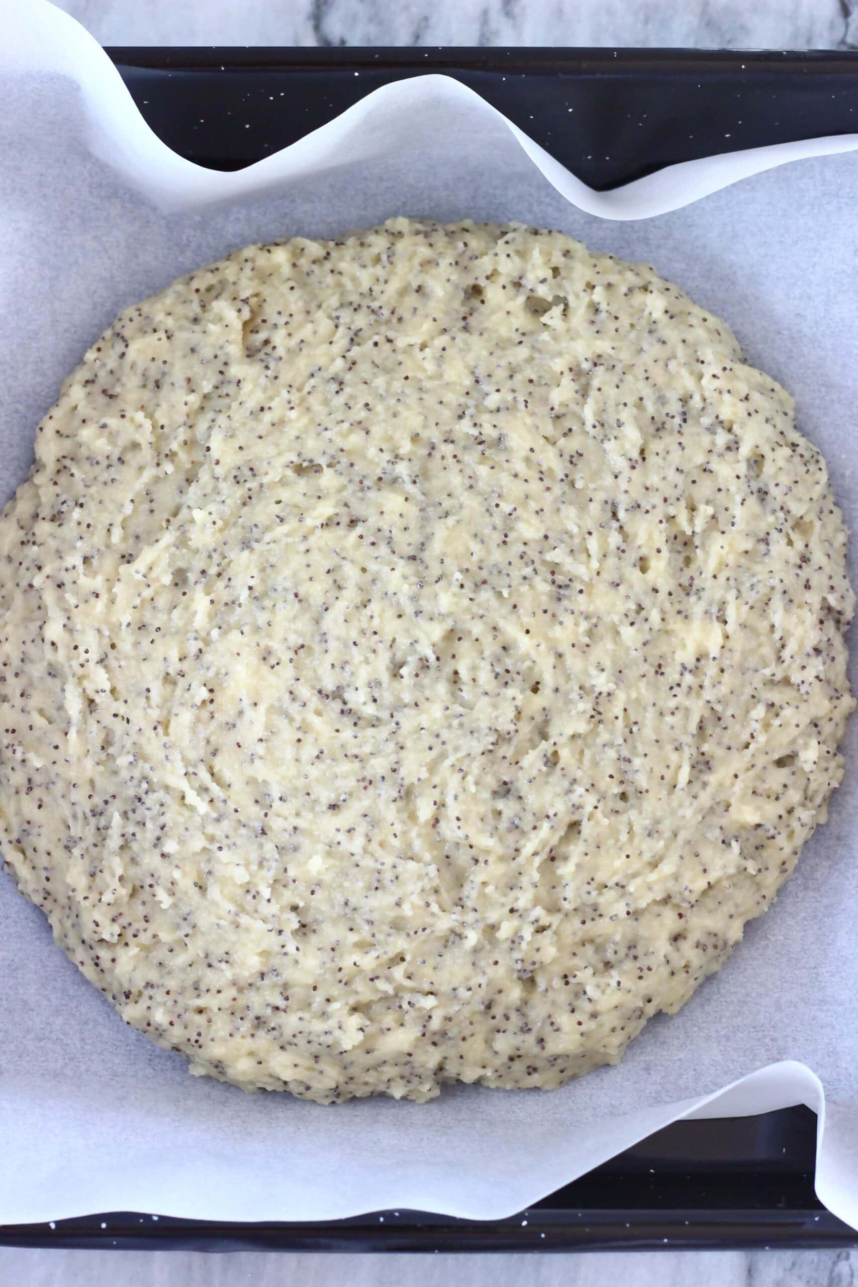 A circle of raw gluten-free vegan lemon poppy seed scones dough on a baking tray lined with baking paper