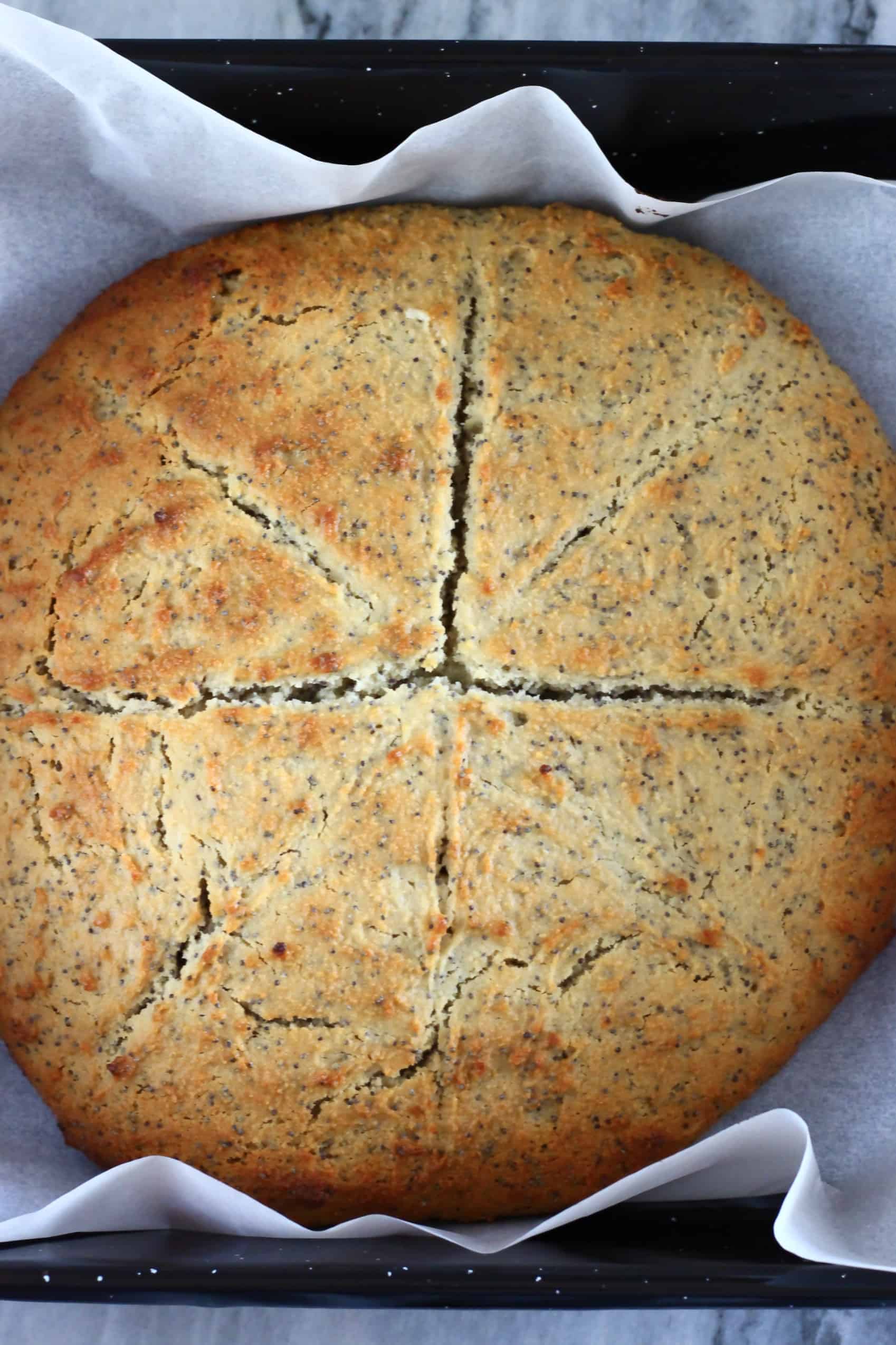 A baked circle of gluten-free vegan lemon poppy seed scones dough on a baking tray lined with baking paper