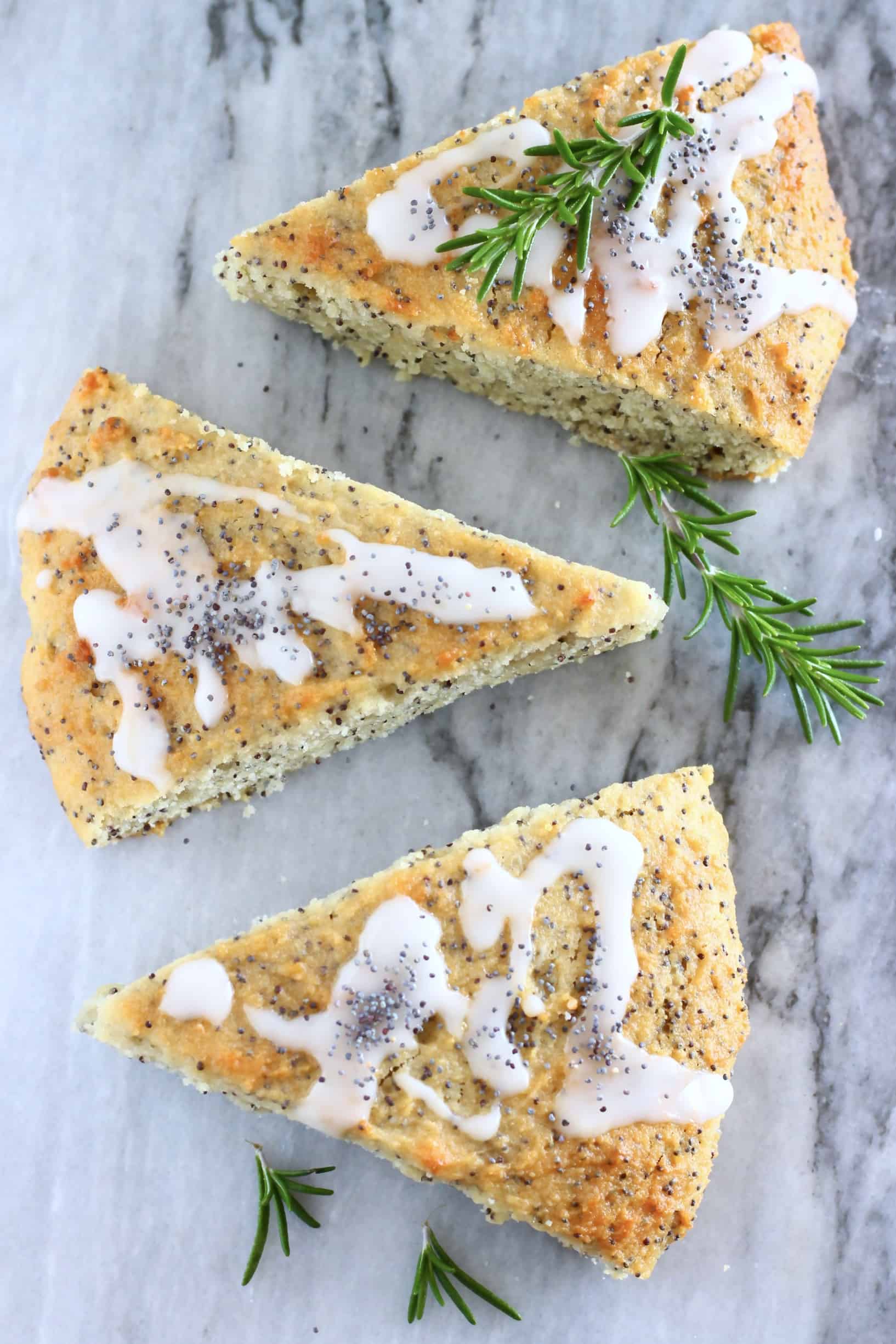 Three triangular gluten-free vegan lemon poppy seed scones on a marble background