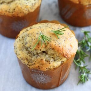 Three gluten-free vegan orange poppy seed muffins on a marble background