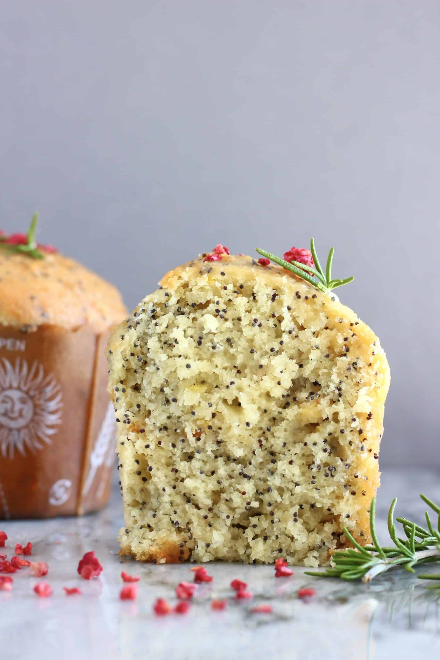 A halved gluten-free vegan orange poppy seed muffin with a whole muffin in the background