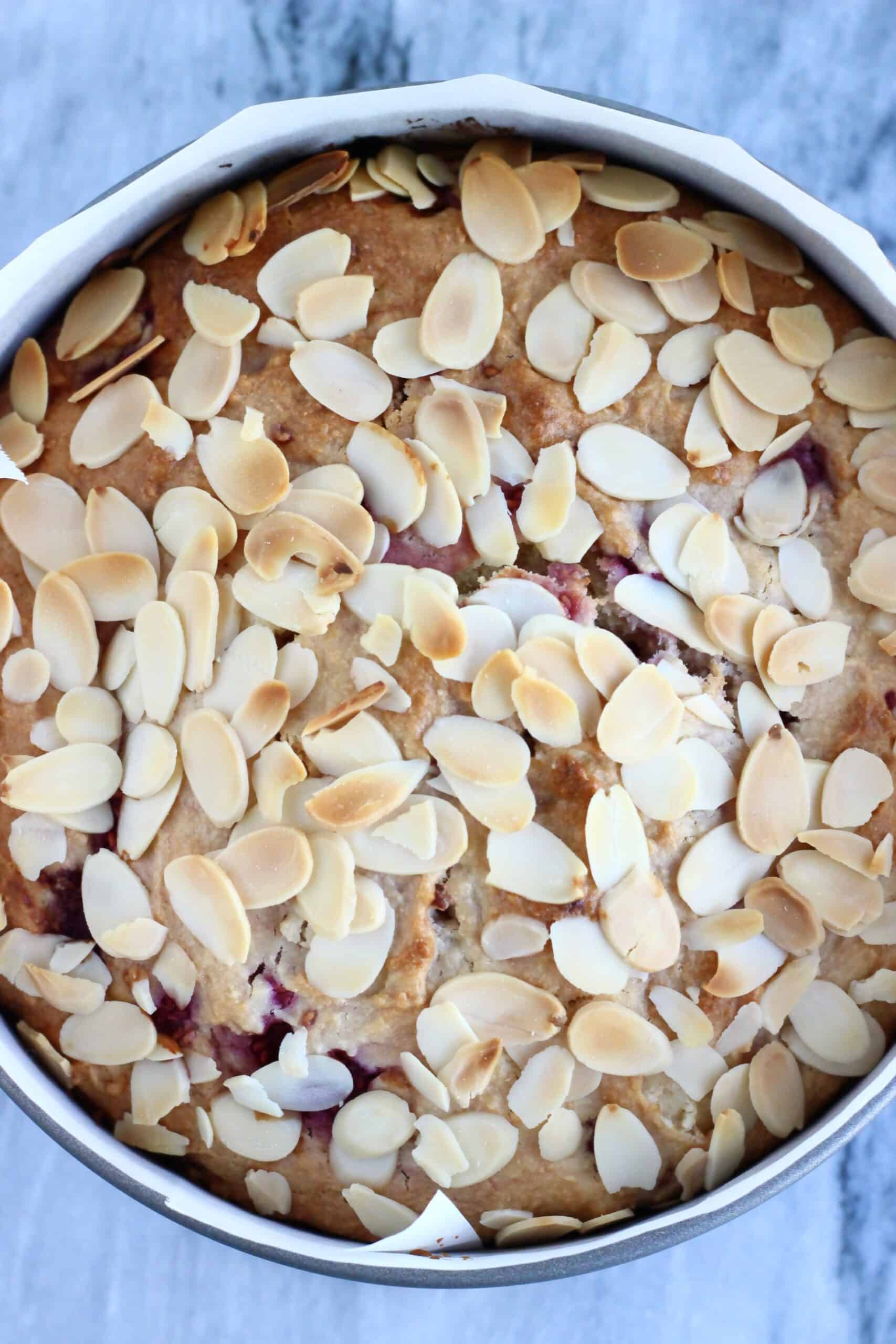 Baked gluten-free vegan raspberry cake in a springform baking tin lined with baking paper