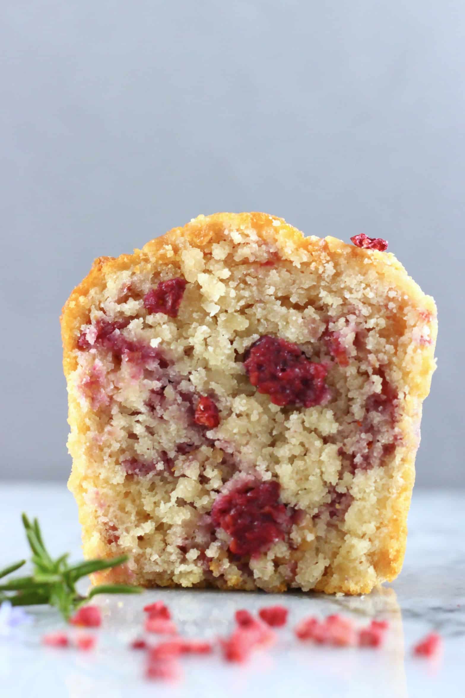 A halved gluten-free vegan raspberry muffin on a marble background