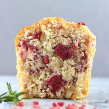 A halved gluten-free vegan raspberry muffin on a marble background