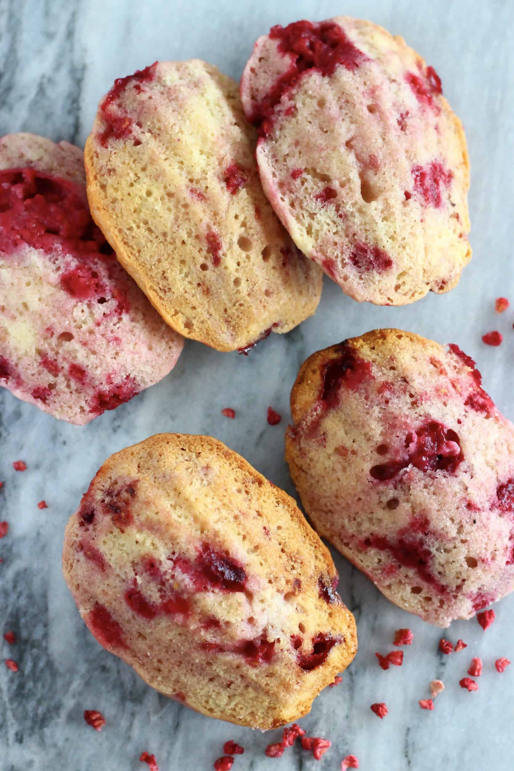 Five gluten-free vegan raspberry madeleines on a marble background